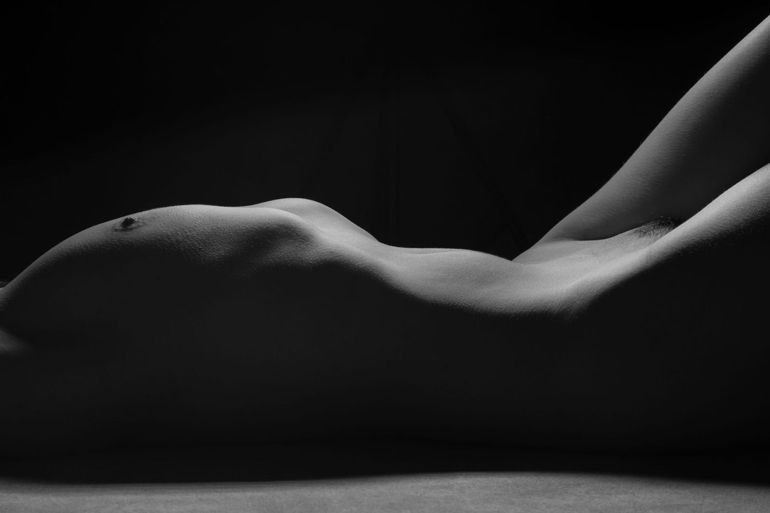 Black and white fine art nude photography highlighting the curves of a reclining female form. Boudoir photography Christchurch bodyscape