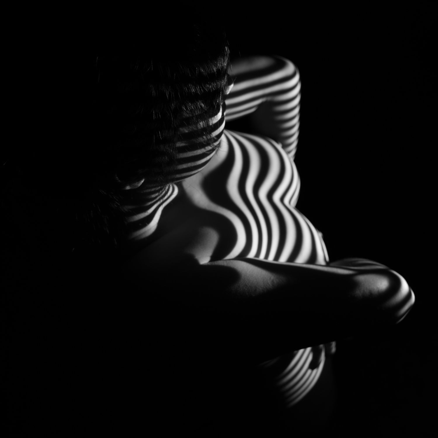 Black and white artistic nude photography with zebra stripe light patterns on a woman's front. Boudoir photography Christchurch