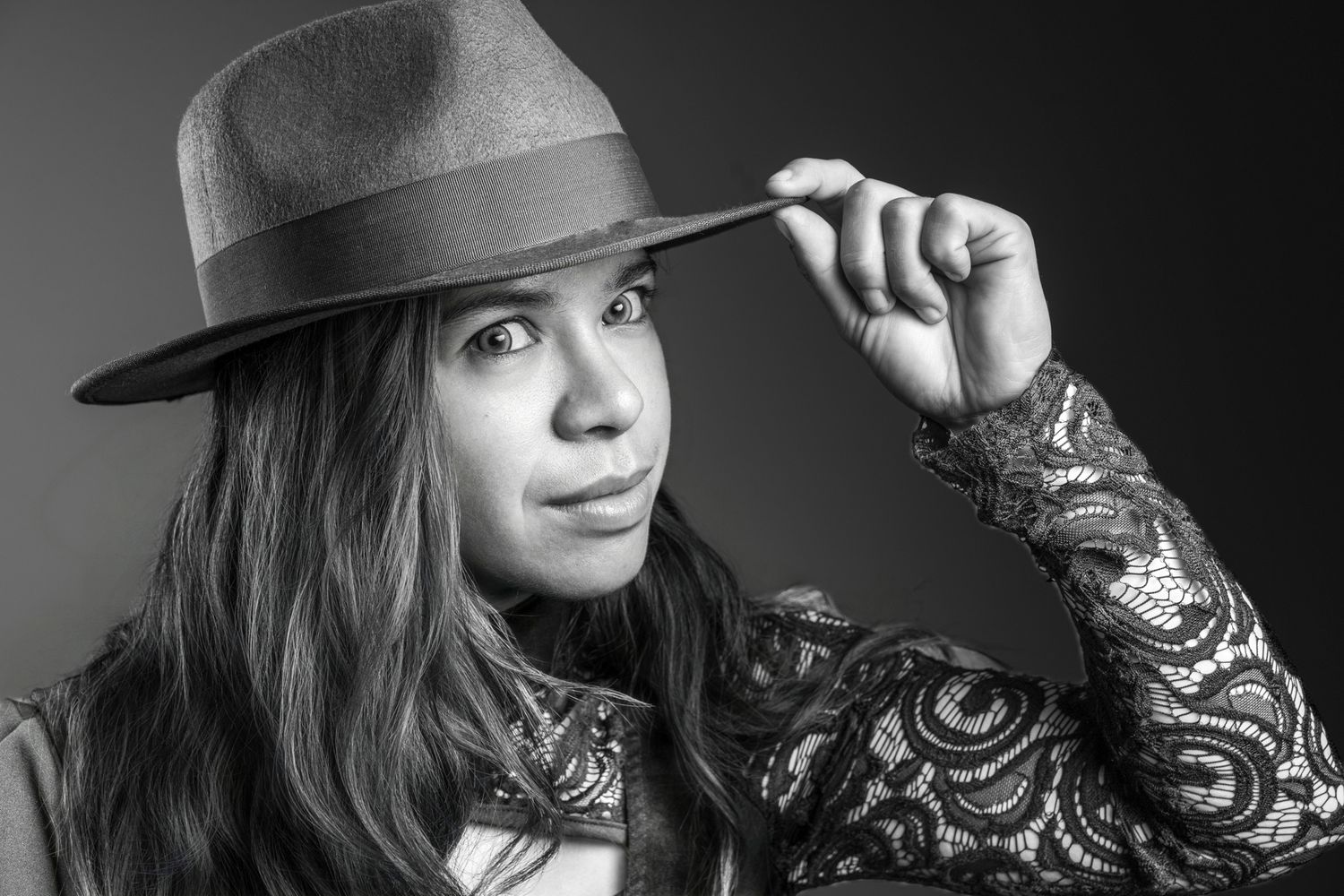 Black and white portrait of a woman in lace top tipping a wide-brim fedora hat stylishly. portrait photography Christchurch