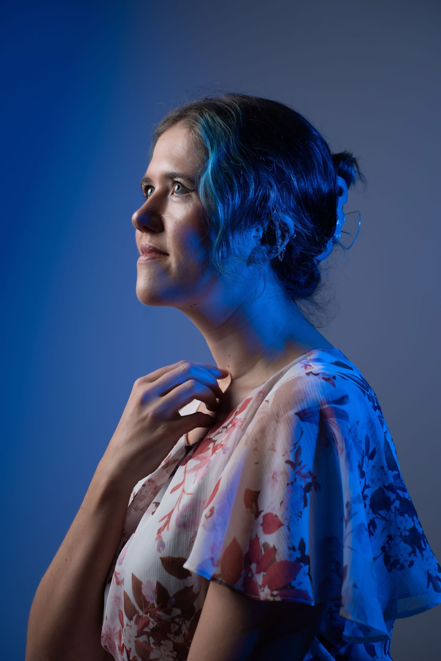 Woman in floral dress posed under dramatic blue studio lighting for a portrait photo. portrait photography Christchurch