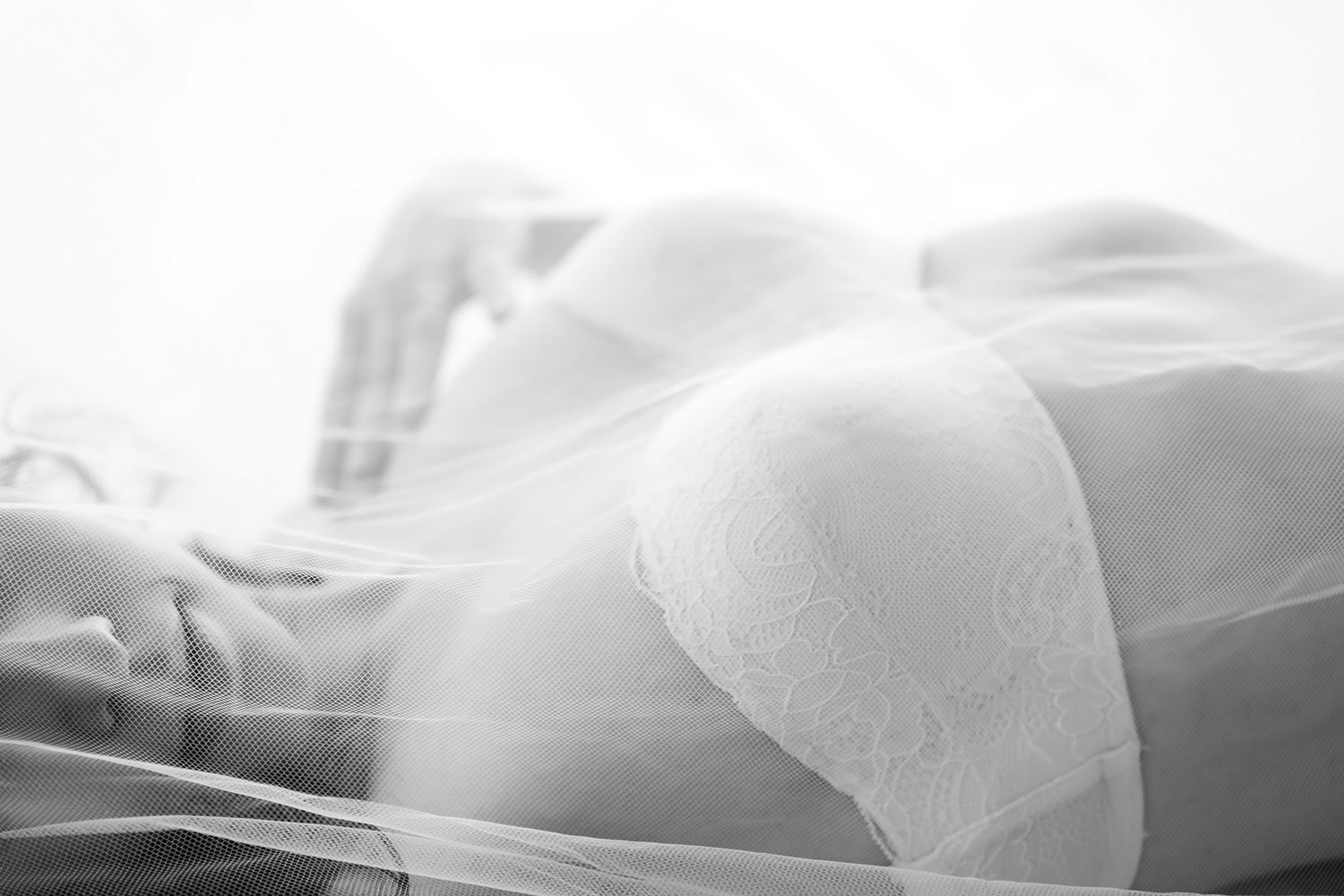 Black and white close-up of a woman in white lace bra covered by a sheer veil. Boudoir photography Christchurch