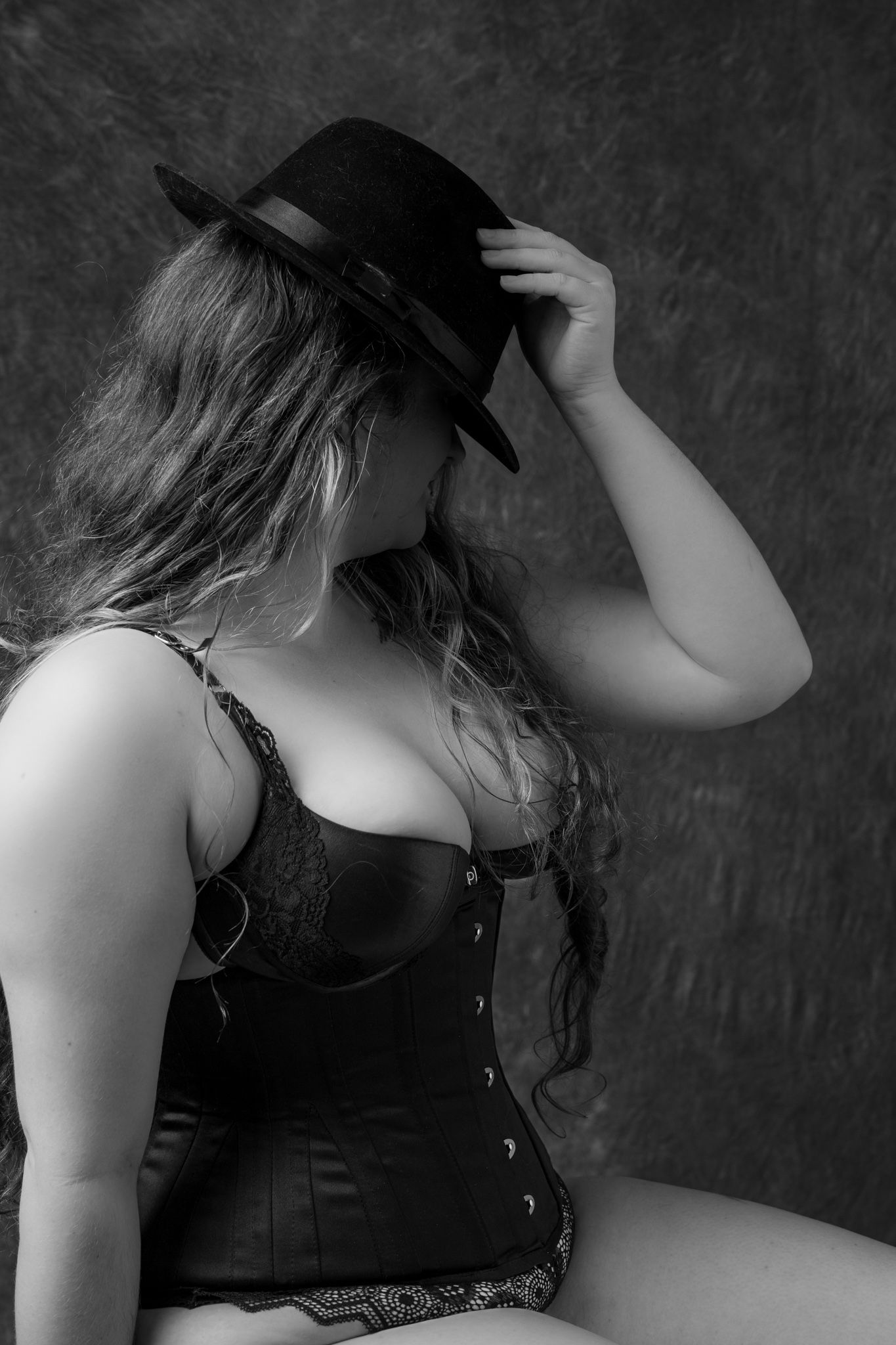 Woman in black corset and hat posing in a black and white boudoir portrait. Boudoir photography Christchurch
