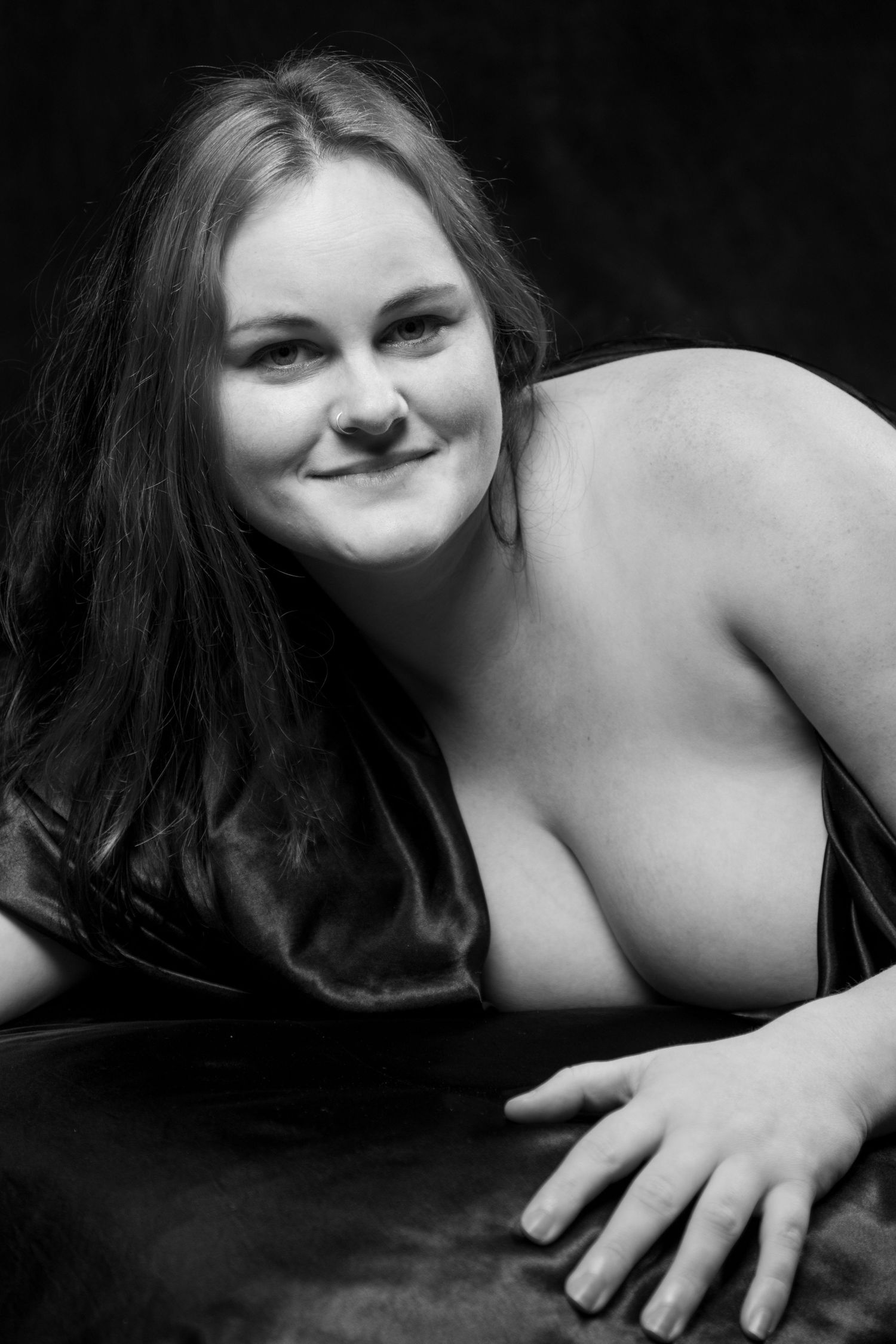 Smiling plus-size woman posing in a black and white studio boudoir photography session. Boudoir photography Christchurch