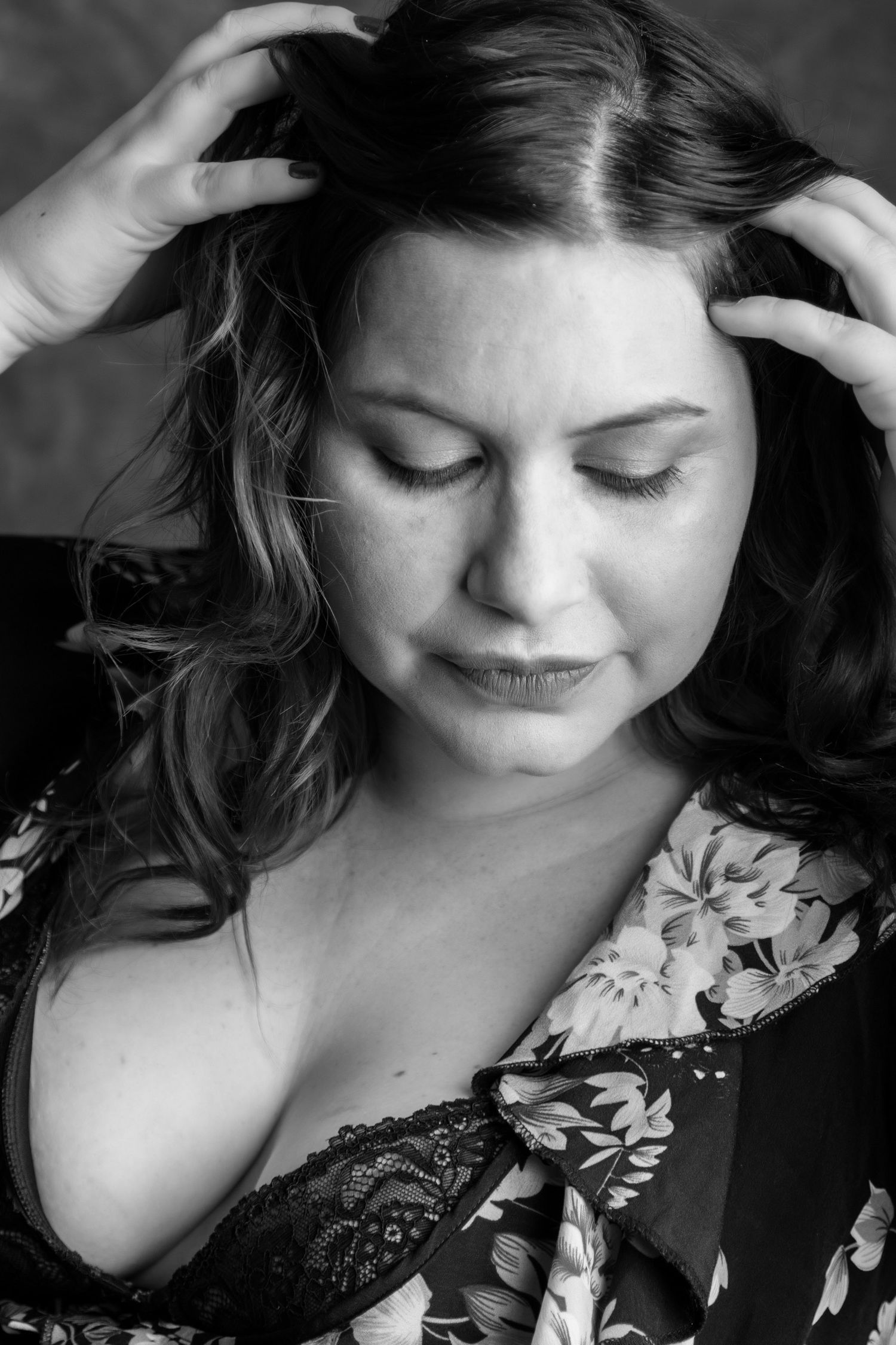 Black and white portrait of a woman in floral robe with hands in her hair. Boudoir photography Christchurch maternity