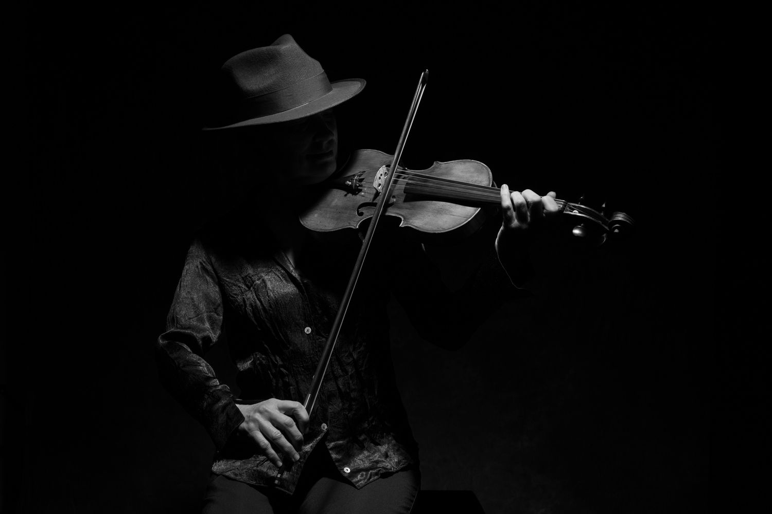 Black and white dramatic shot of a musician in a cowboy hat playing violin on stage. portrait photography Christchurch