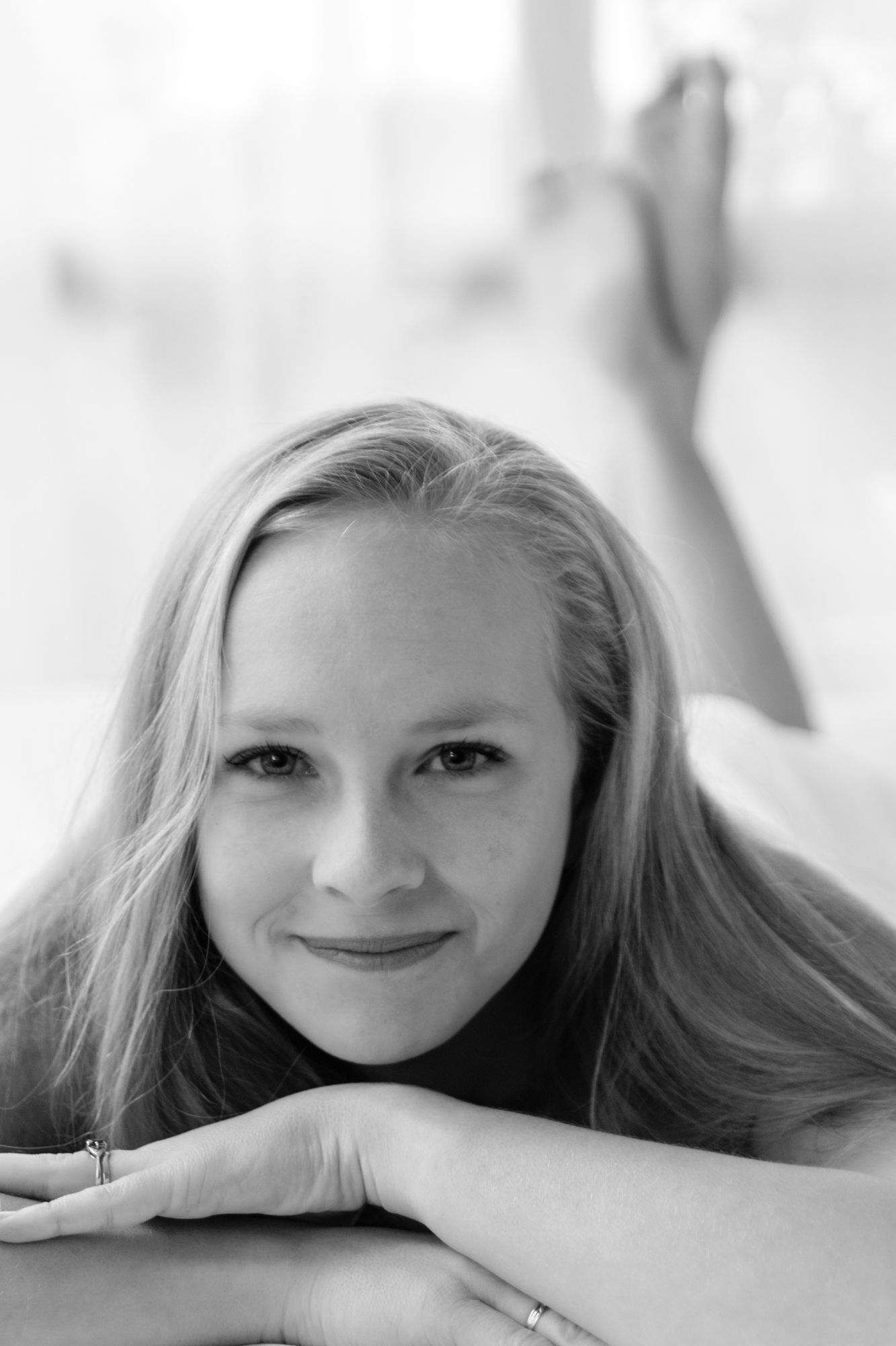 Young blonde woman lying down smiling at camera, elegant black and white portrait photography. Boudoir photography Christchurch
