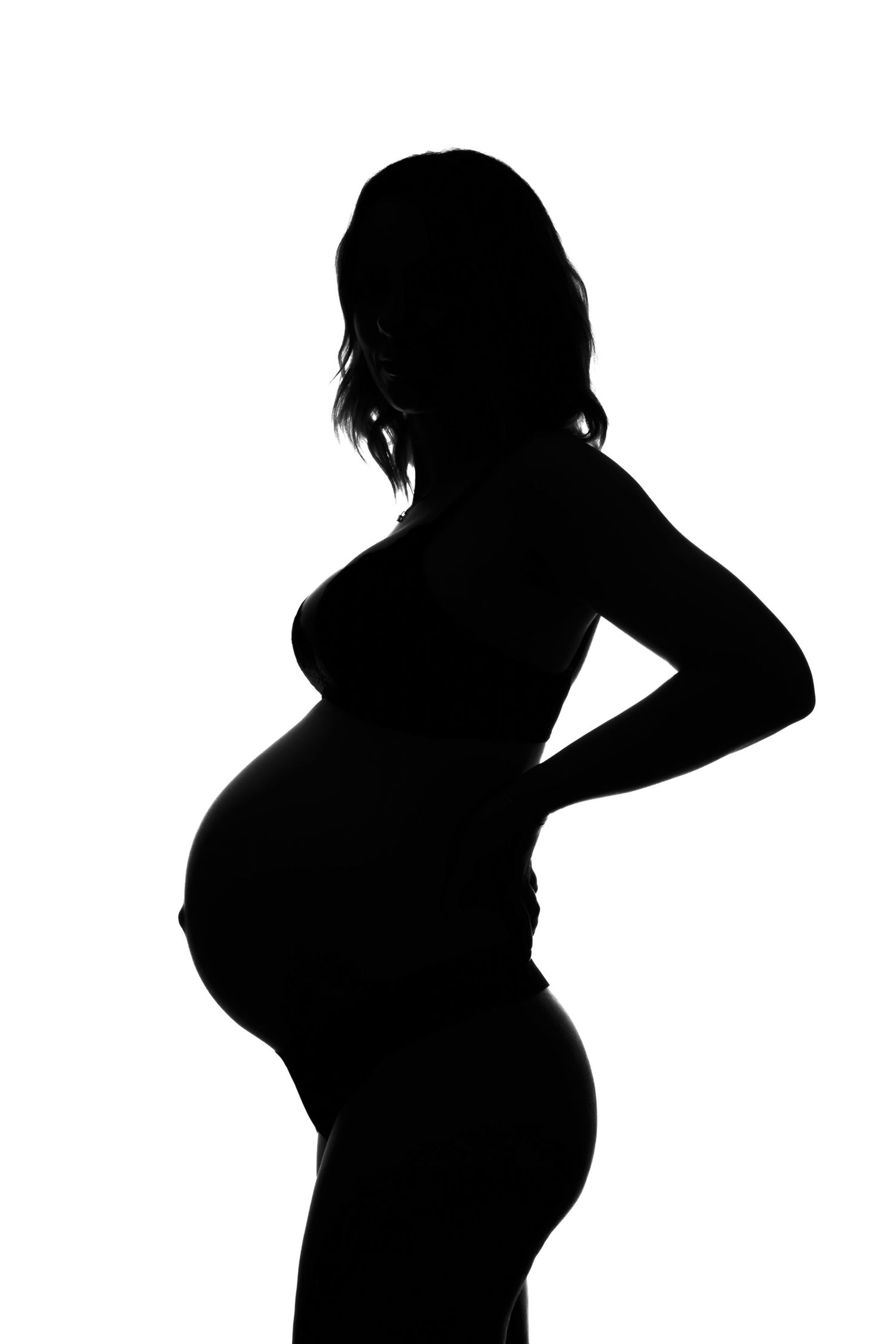 Silhouette of pregnant woman against white background showing profile of baby bump in B&W photo.  Boudoir photography Christchurch