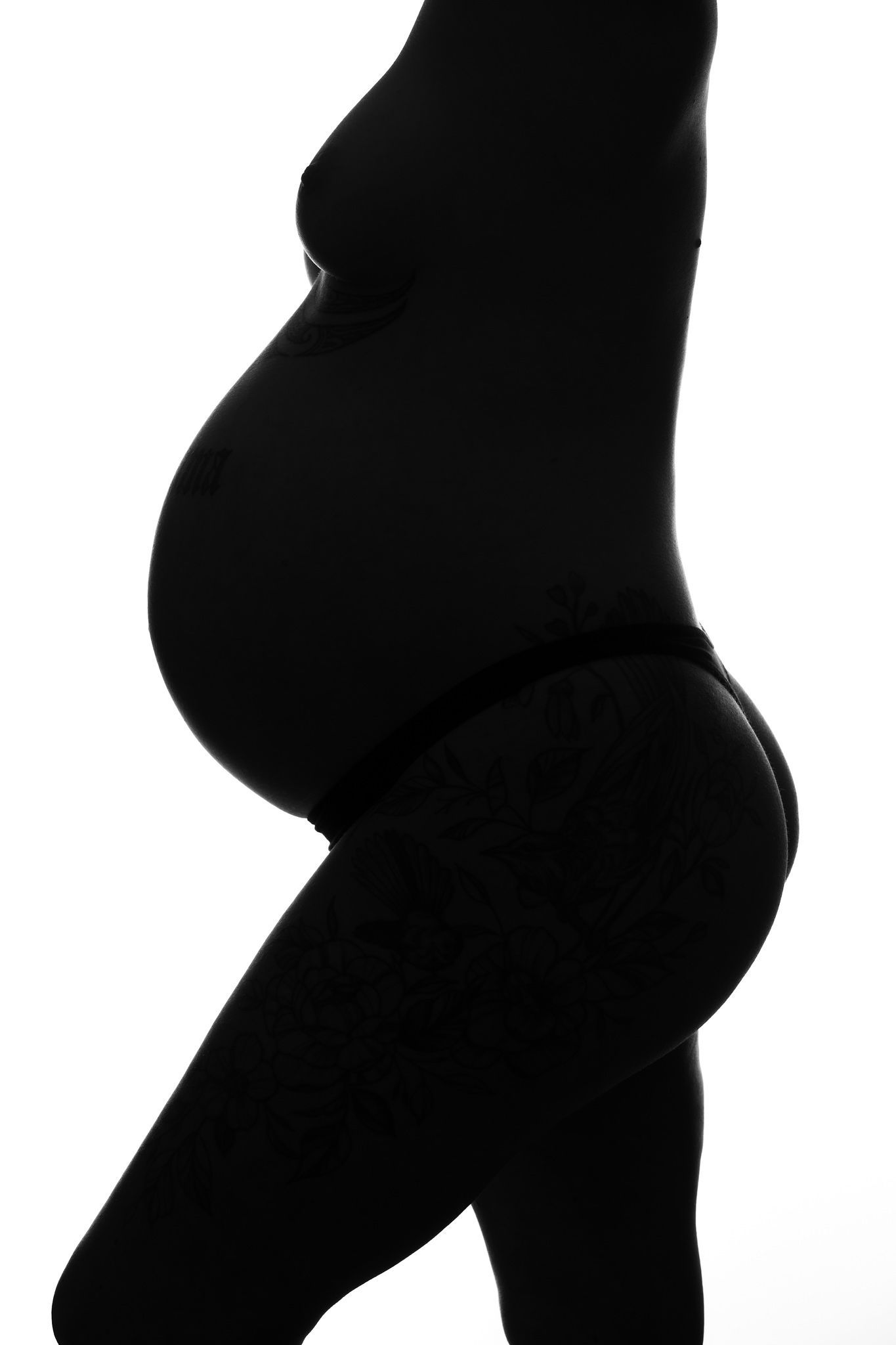 Silhouette of a pregnant woman's profile showing her baby bump against a white background.