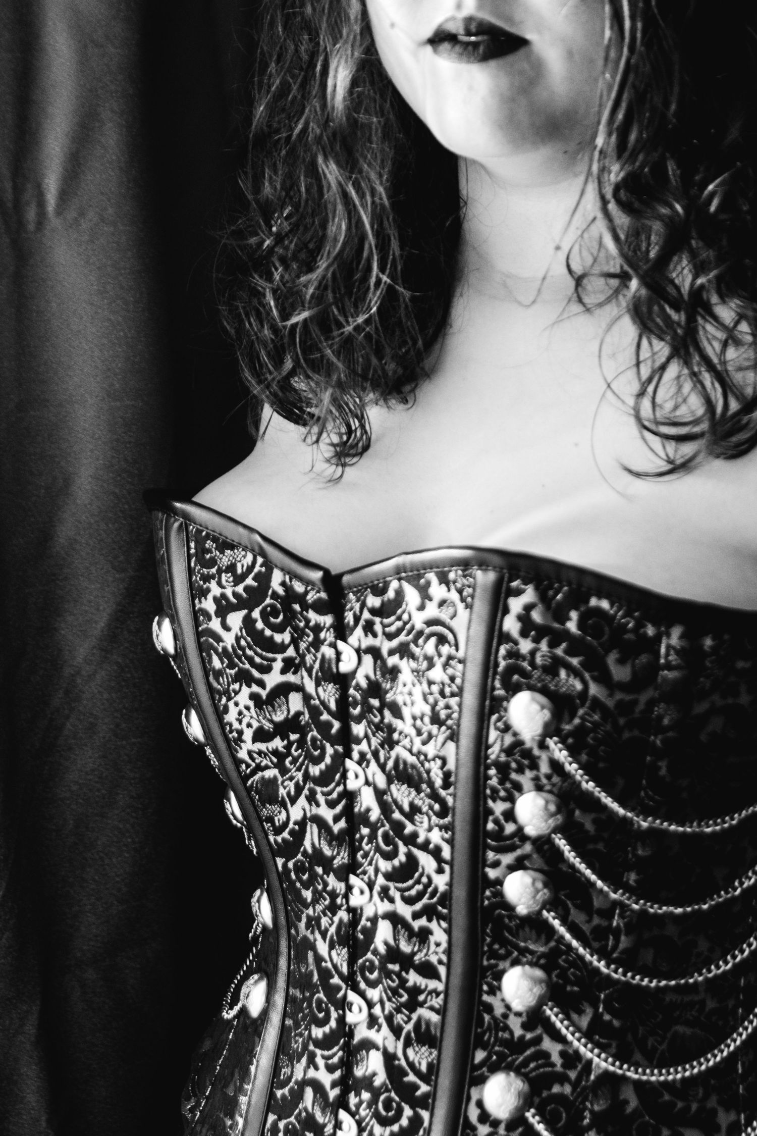 Black and white close-up of ornate brocade corset with pearl and chain embellishments. Boudoir photography Christchurch