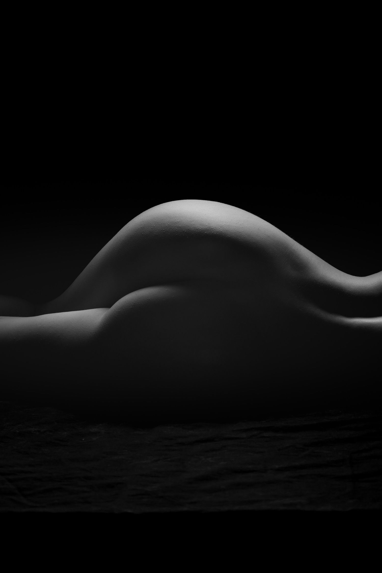 Dramatic black and white fine art nude bodyscape silhouette emphasizing the natural curves of a woman's form. Boudoir photography Christchur