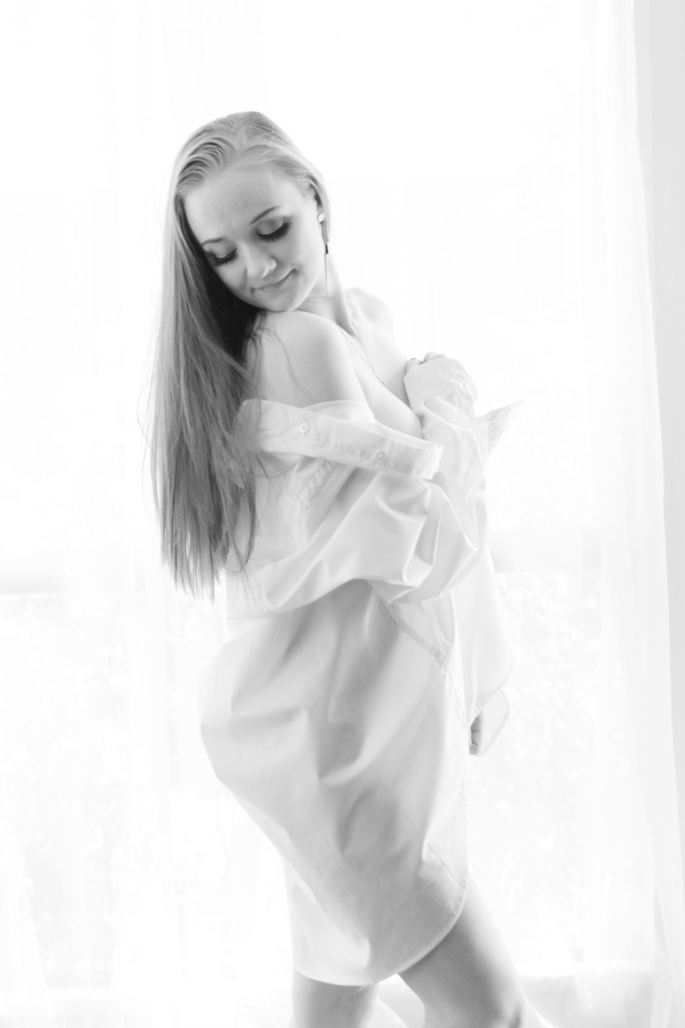 Elegant blonde woman in a sheer white blouse posing softly in a bright high-key black and white portrait. Boudoir photography Christchurch