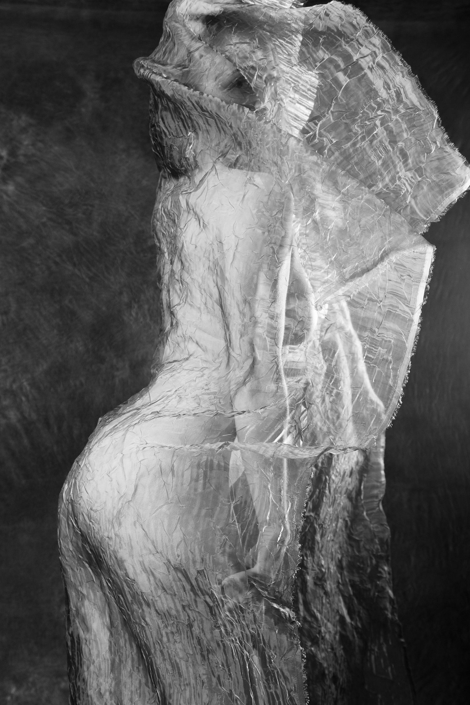 Black and white artistic photo of a nude figure wrapped in crinkled transparent fabric. Boudoir photography Christchurch