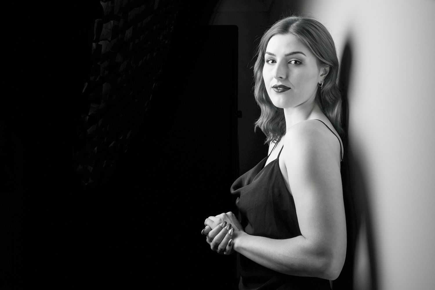Black and white portrait of a woman in a black slip dress leaning against a wall. portrait photography Christchurch
