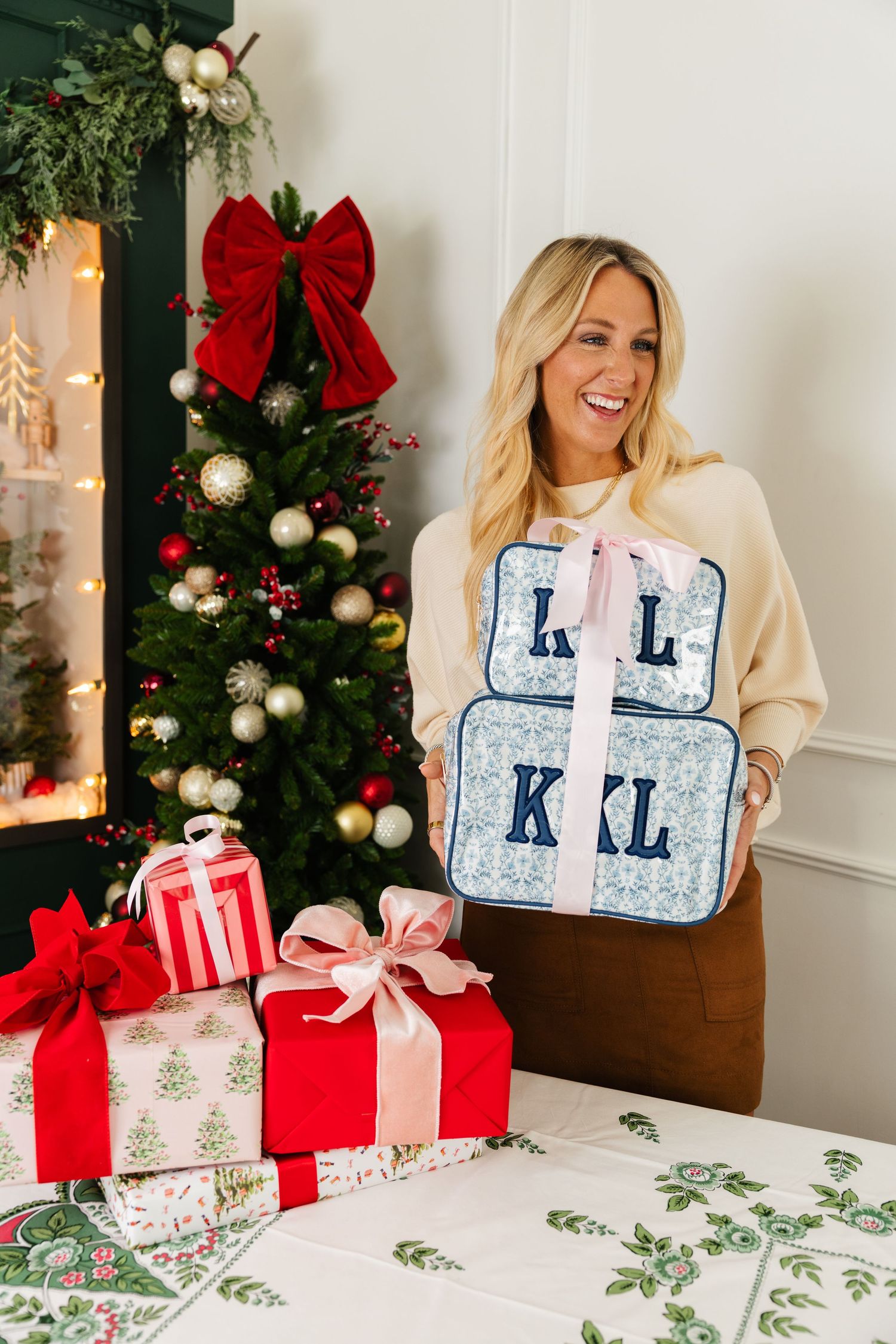 Smiling woman holding two monogrammed KL and KKL floral cosmetic cases.
