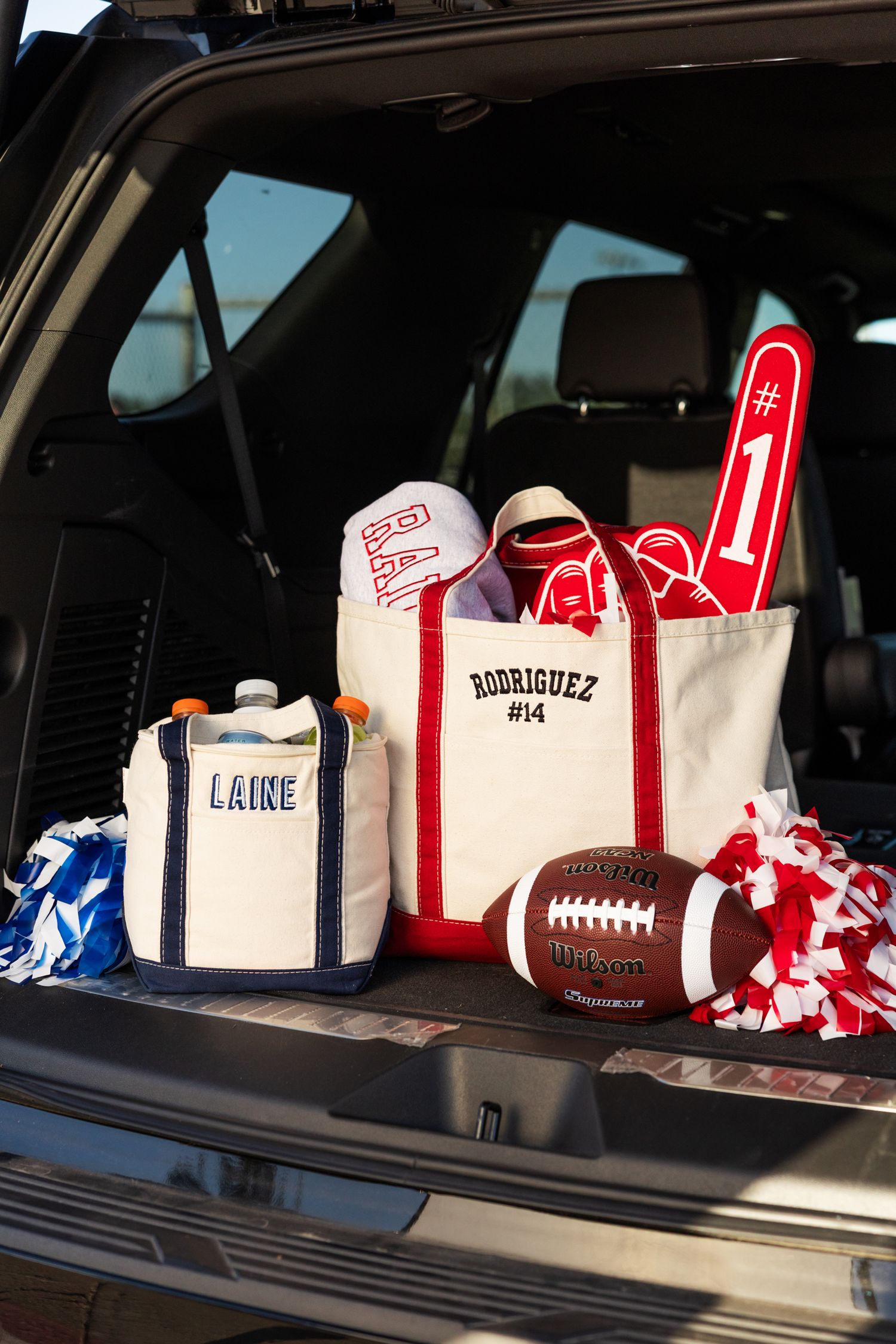 Personalized canvas tote bags and football tailgate gear displayed in an open car trunk.