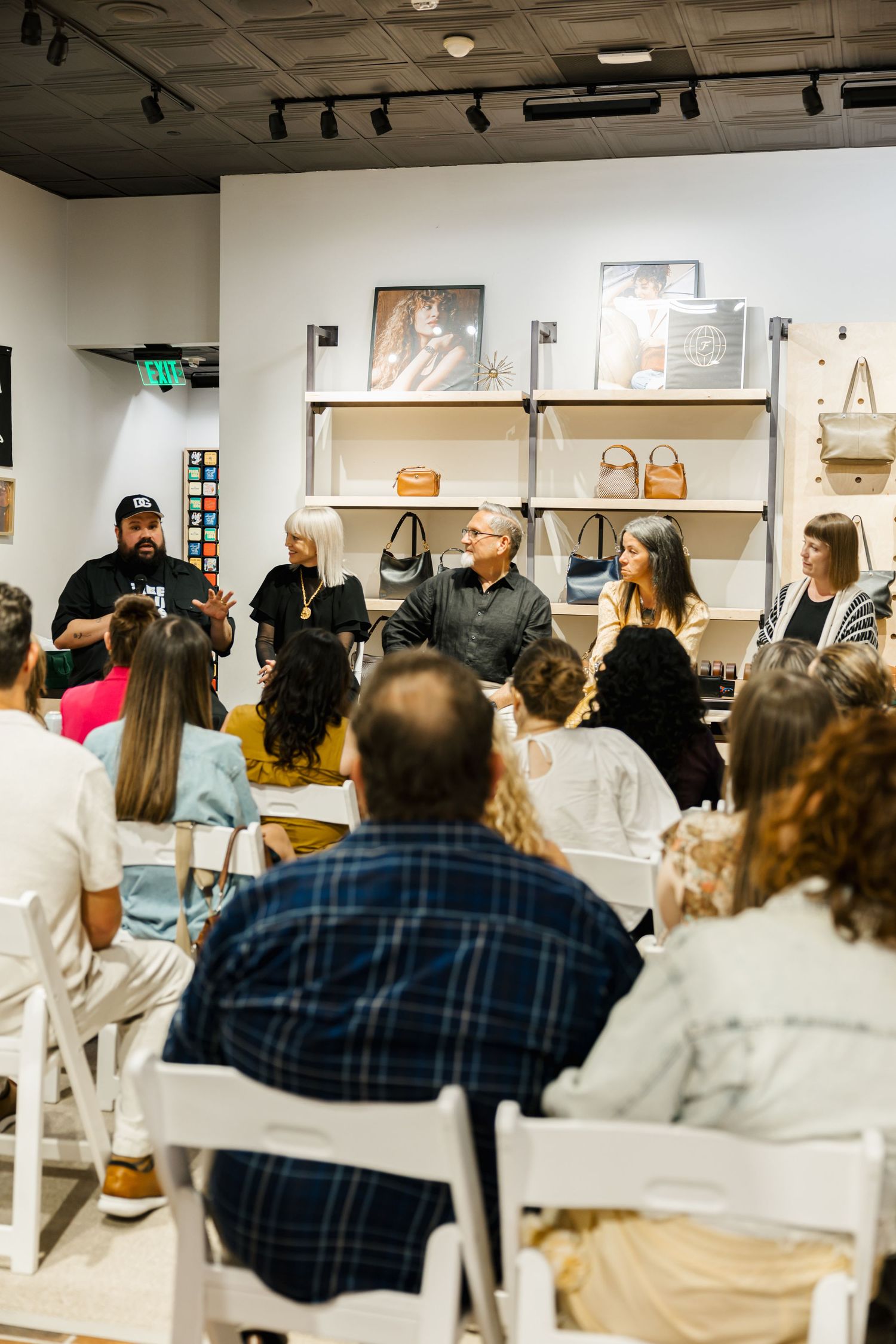 Panel discussion at a boutique store event with speakers seated before an audience in white chairs.