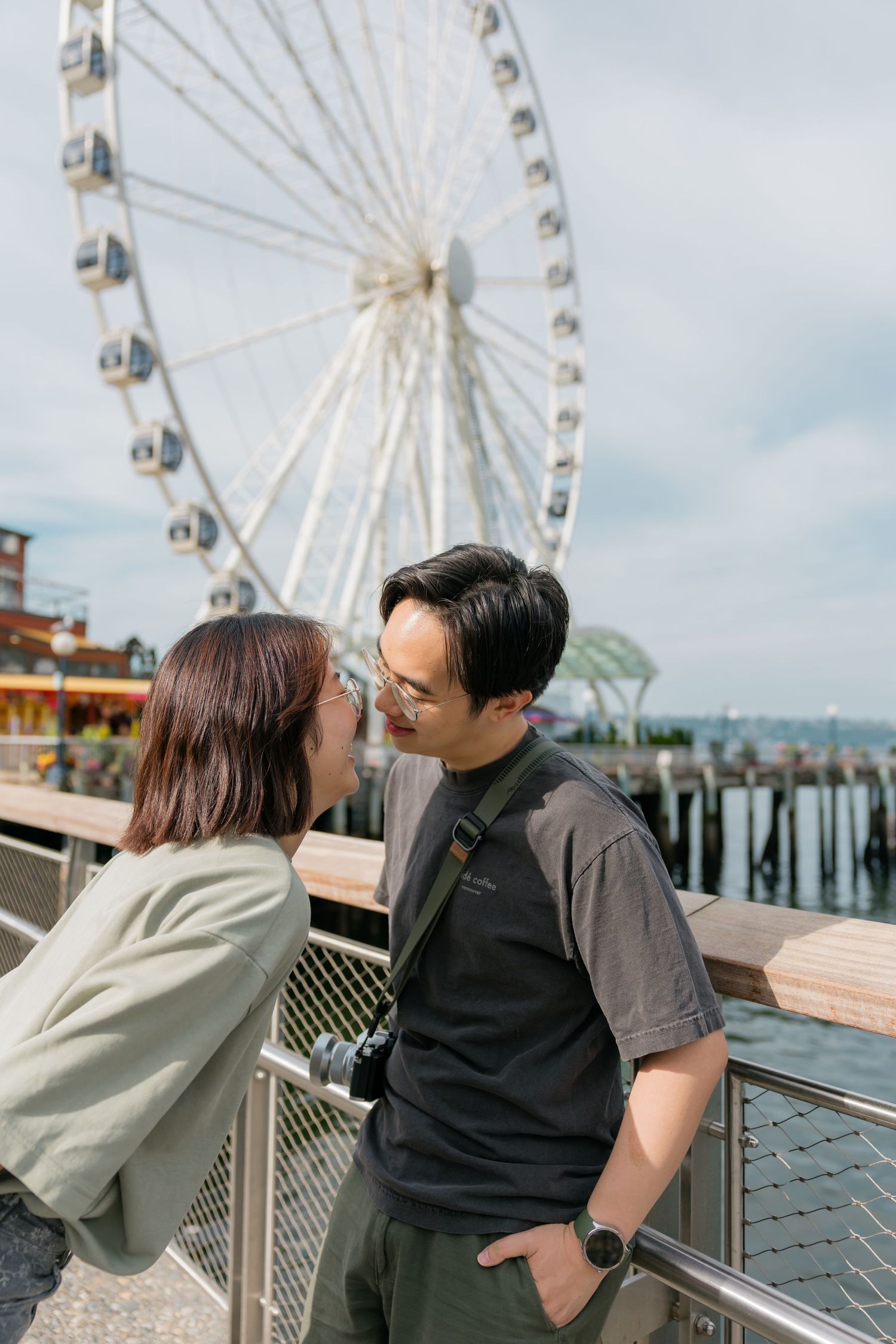 Couple sharing a romantic moment in front of the Seattle Great Wheel ferris wheel on the waterfront pier.