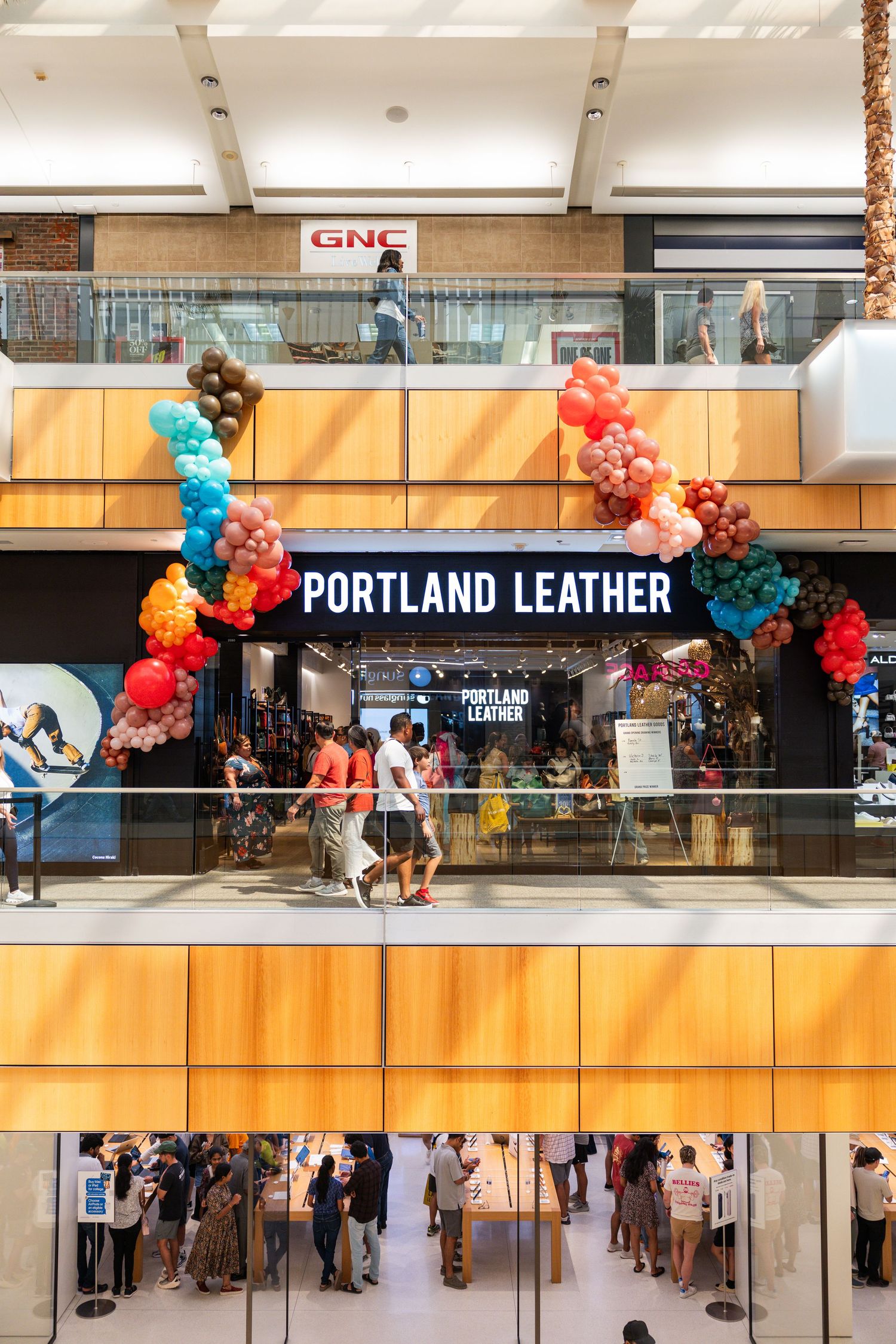 Portland Leather store grand opening decorated with colorful balloon arch in a shopping mall.