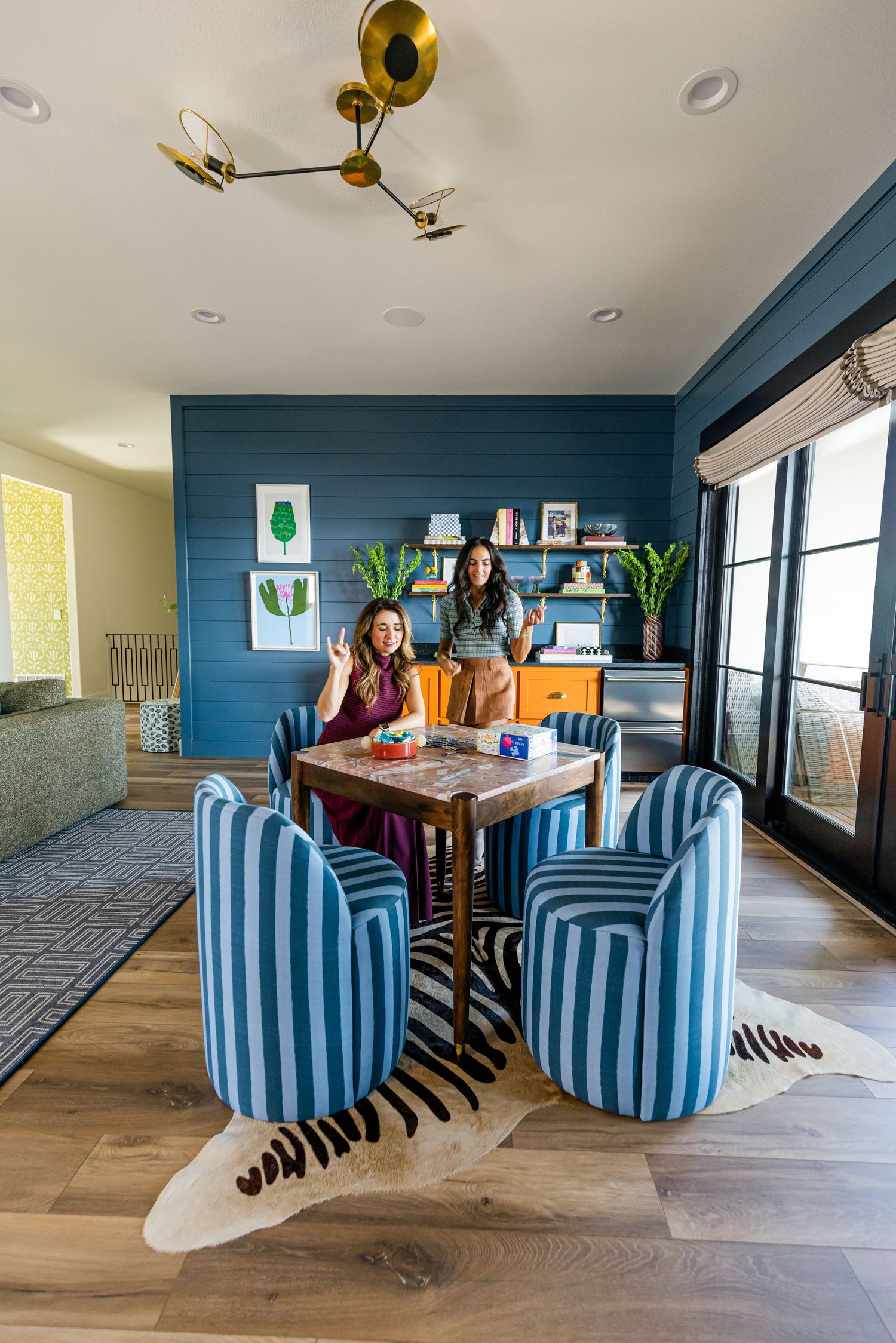 Blue striped dining chairs around wood table on zebra rug in vibrant blue shiplap game room.