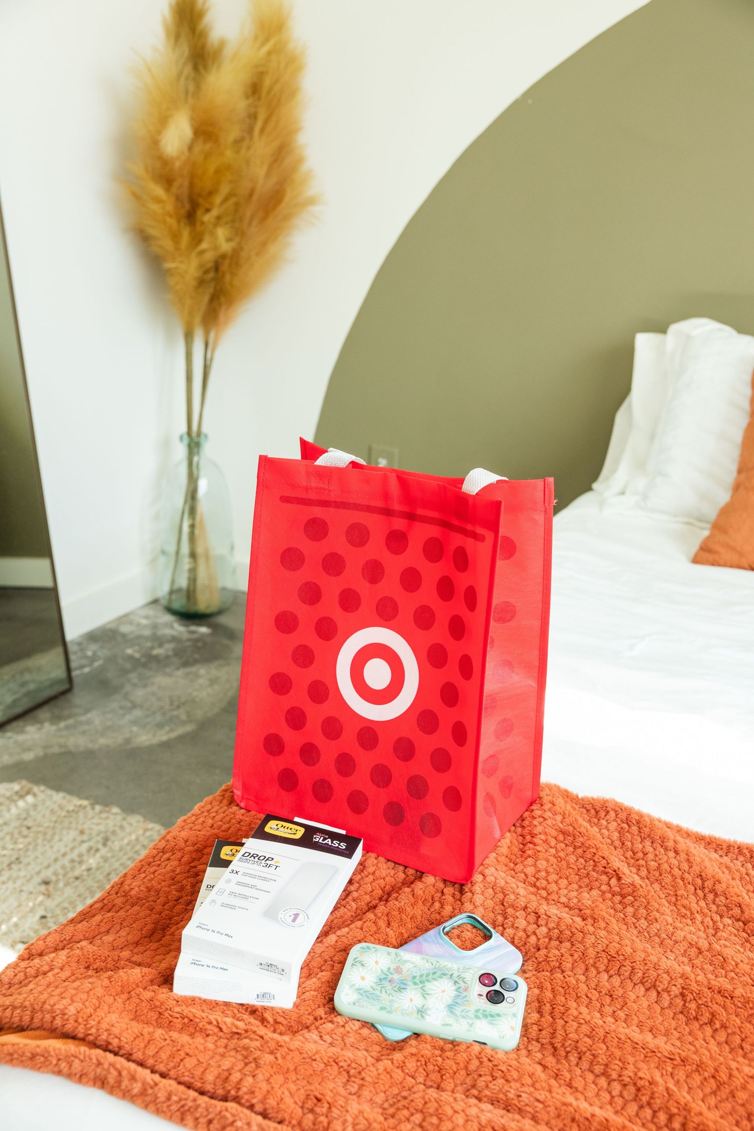 Red Target shopping bag with receipt and gift cards on an orange blanket in a modern bedroom.