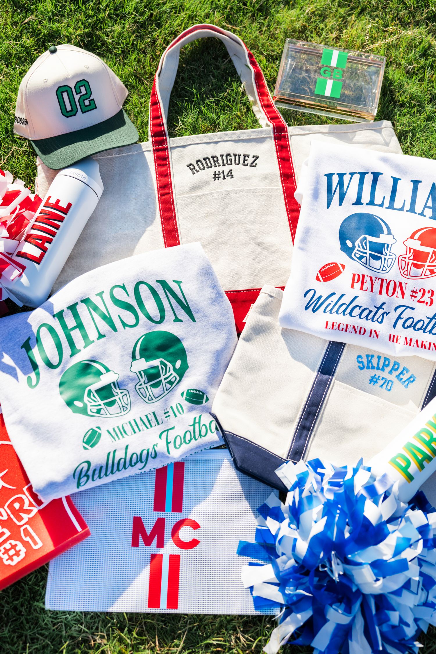 Personalized football fan gear including monogrammed tote bags, water bottles, and apparel displayed on grass.