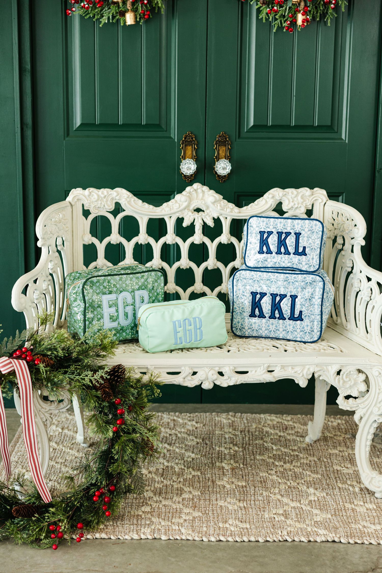 Monogrammed KKL and EGB cosmetic cases on white ornate bench with holiday decor.