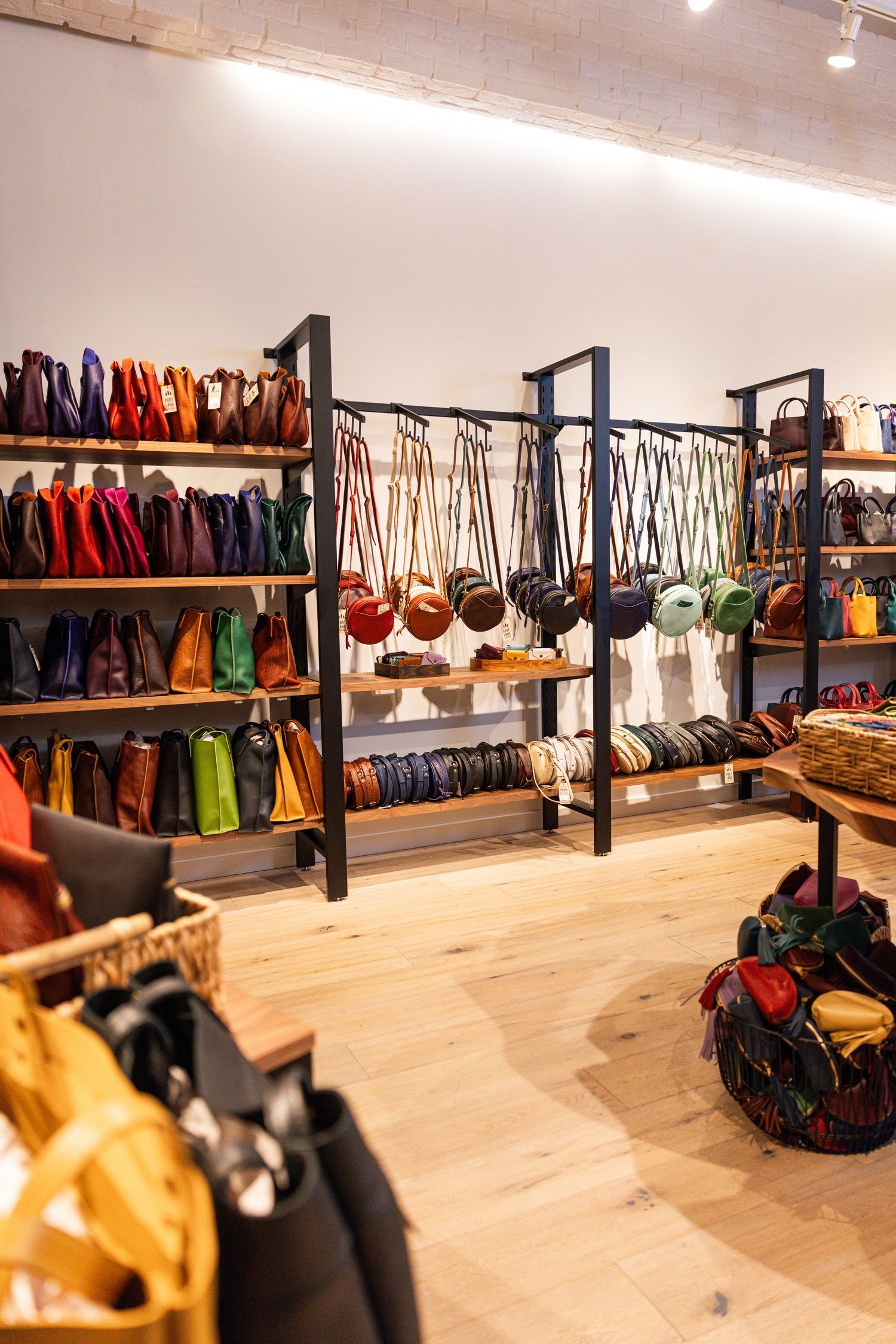 Colorful leather handbags and crossbody bags displayed on shelves inside Portland Leather store.