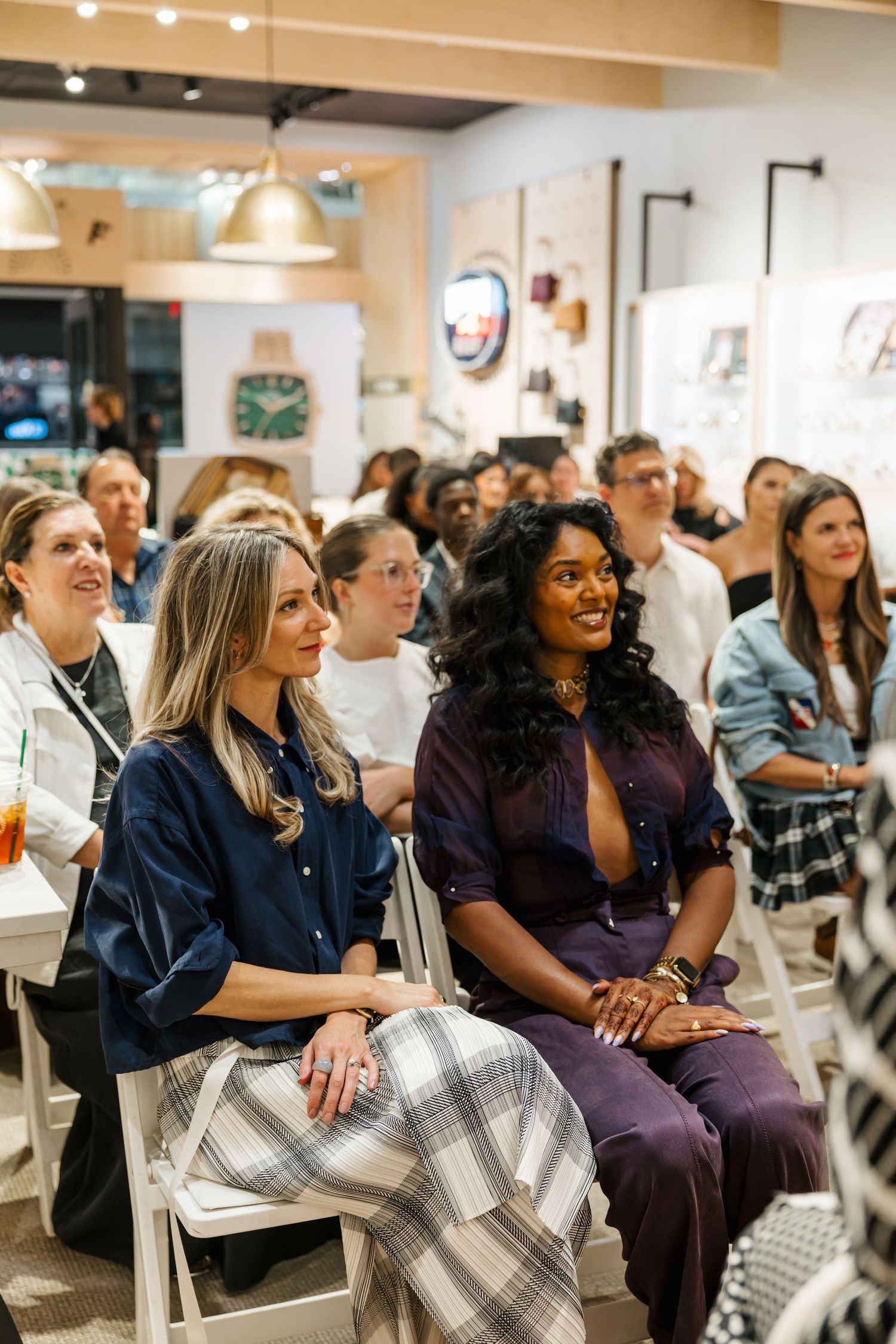 Diverse audience smiling and engaged at a crowded boutique panel discussion event.