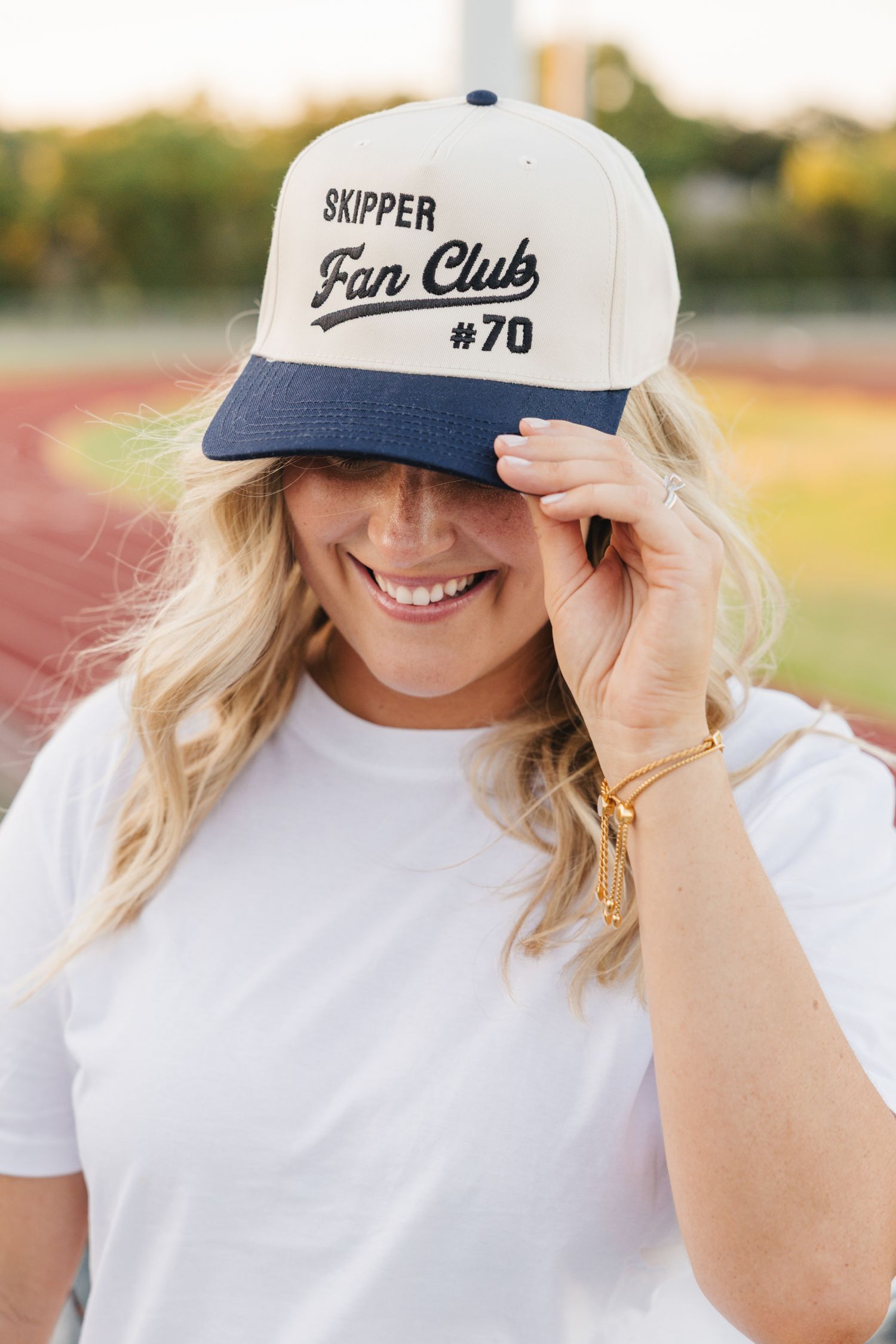 Smiling woman wearing a personalized navy and cream Skipper Fan Club #70 snapback cap outdoors.