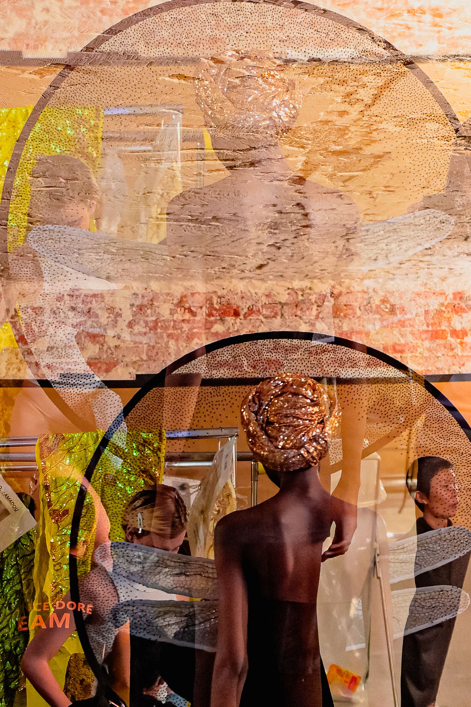 Artistic double exposure fashion photo featuring a model in a gold head wrap at a vibrant backstage of Rahul Mishra fashion show.
