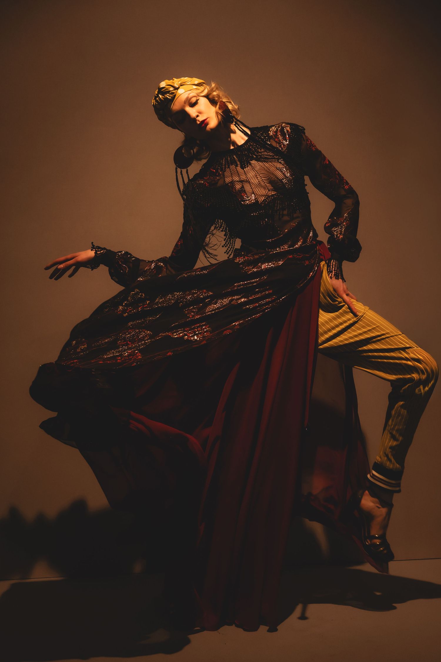 Elegant model during the first looks of Julien Fournié  in a flowing dark embroidered gown performs dramatically under warm studio lighting.