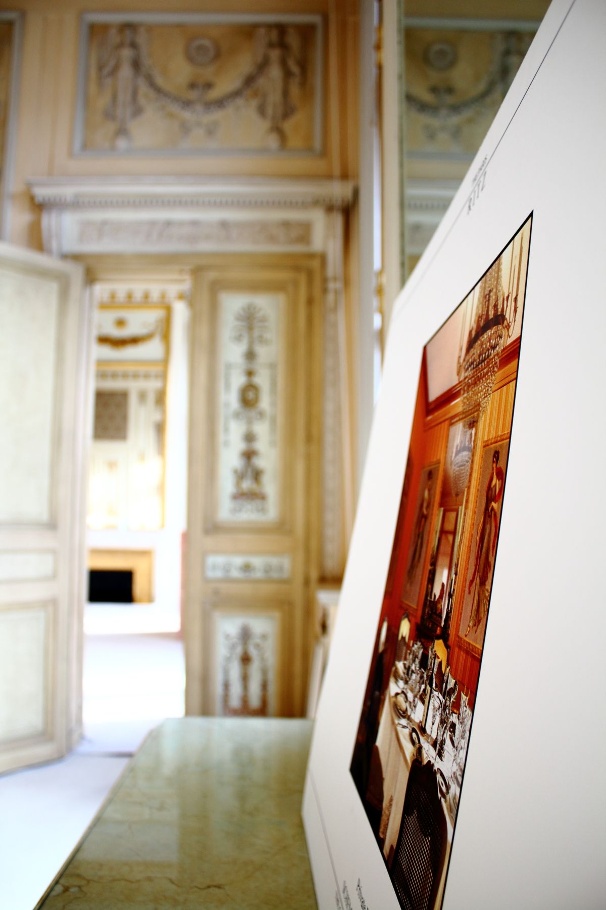 Ornate French palace room with decorative painted walls and a photograph displayed on a marble surface.