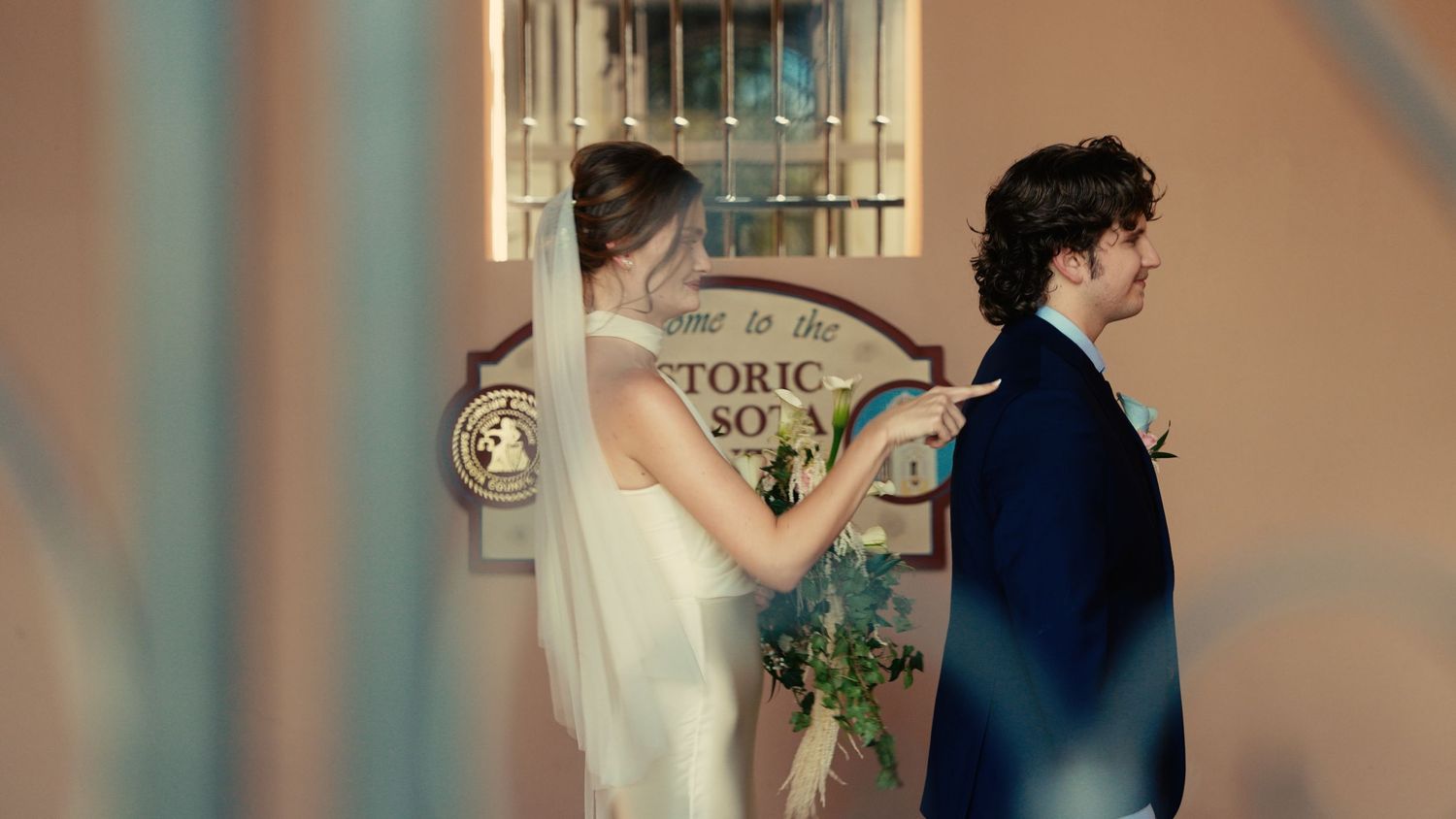Bride and groom standing at Historic Sotano entrance, bride holding blue floral bouquet.