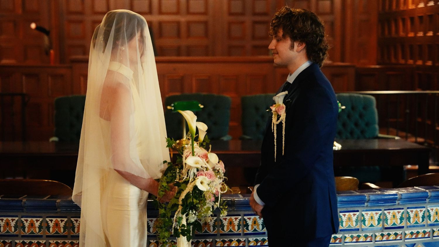 Bride and groom facing each other during wedding ceremony in elegant chapel with blue decor.
