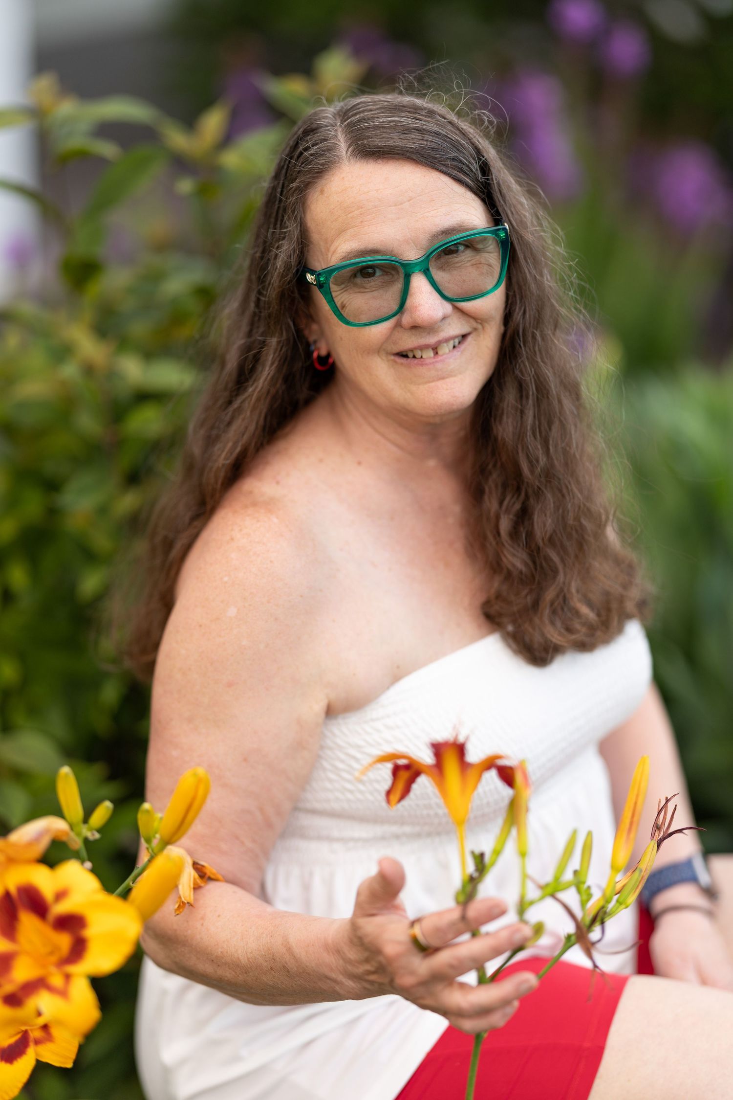 Woman looks into the camera and holds flowers for portrait taken by photographer in Yellow Springs, Ohio