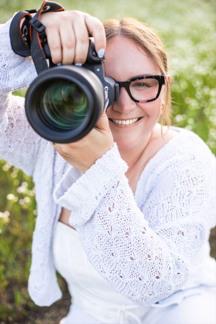 Photographer in Fairborn, Ohio poses for a photo with her camera held up to her face. She is looking through her camera and smiling