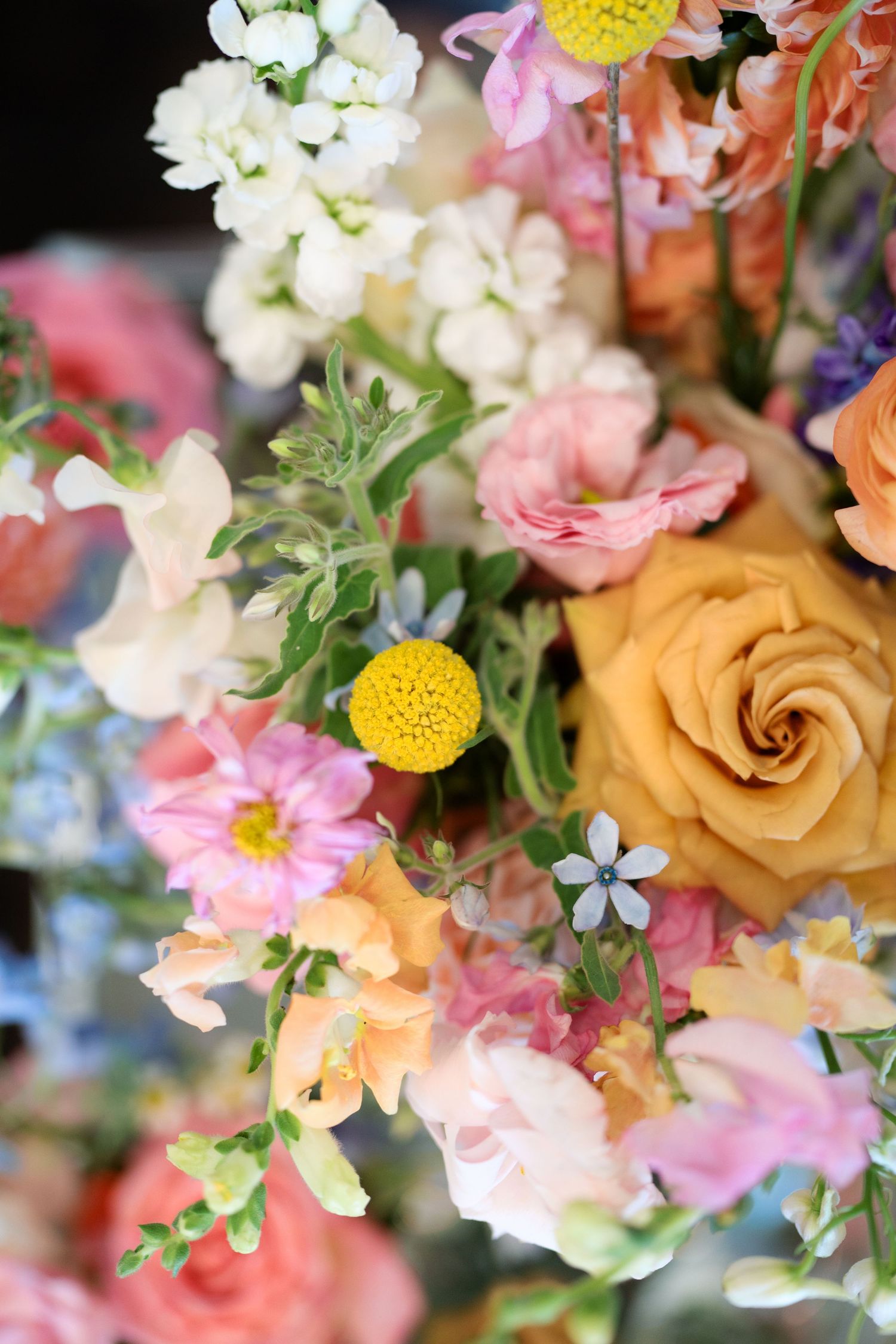 Colorful wedding floral arrangement featuring yellow roses, pink blooms, and wildflowers in a lush bouquet.
