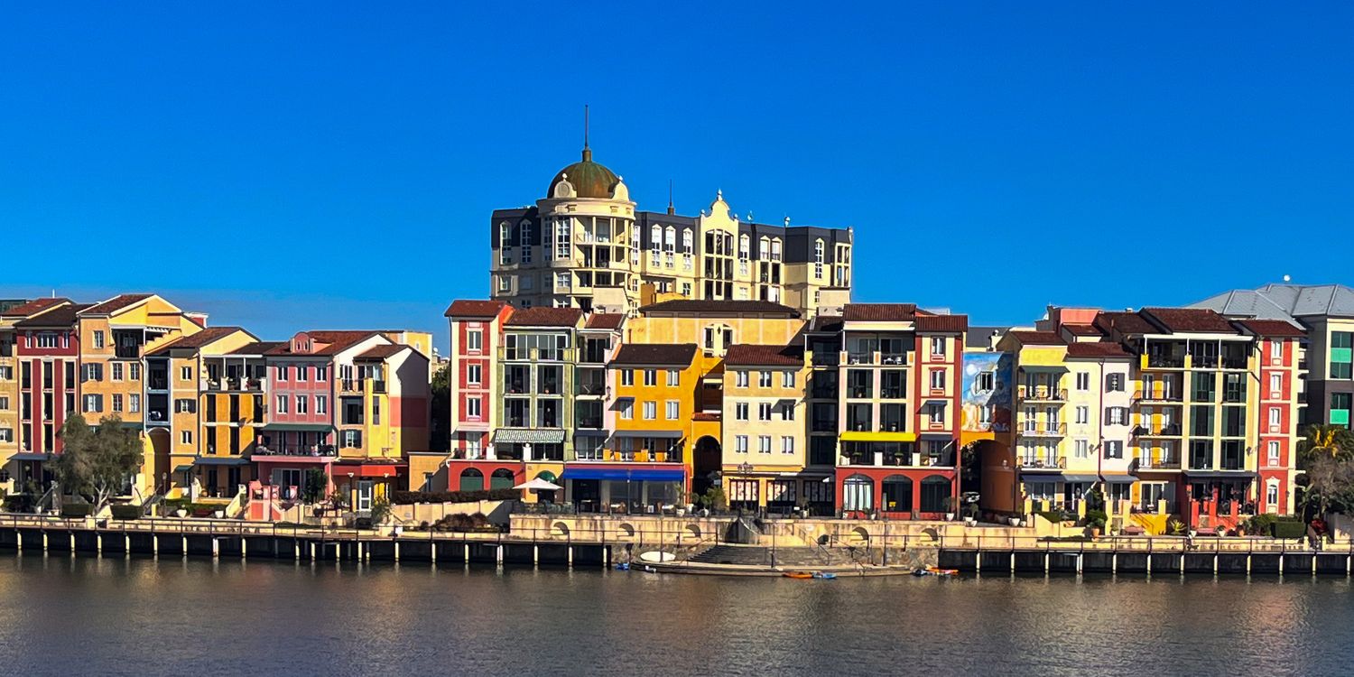 Colorful waterfront buildings reflected in calm water at Portofino Bay Hotel Orlando.