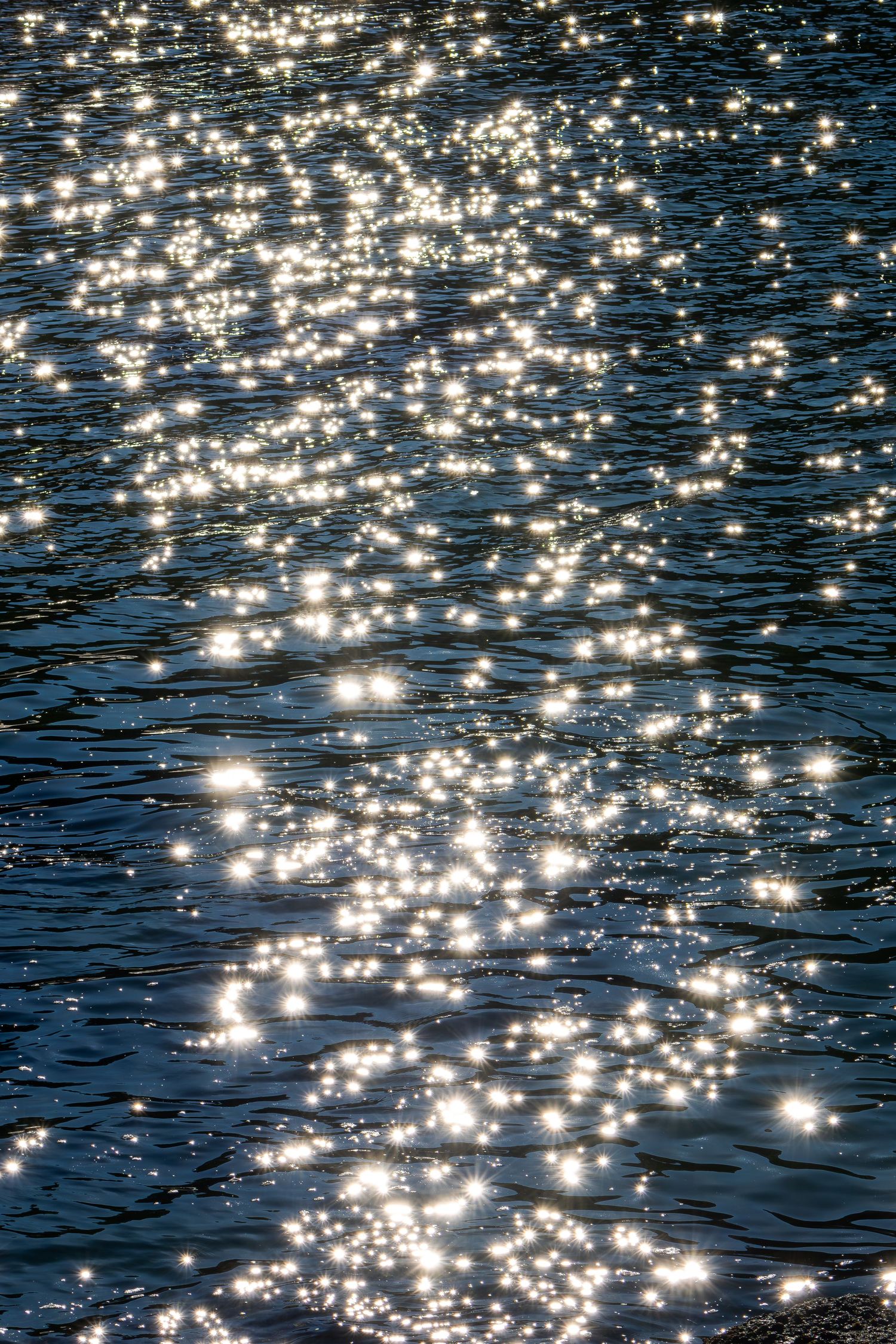 Sunlight sparkling on dark blue rippling water creating brilliant glittering reflections.
