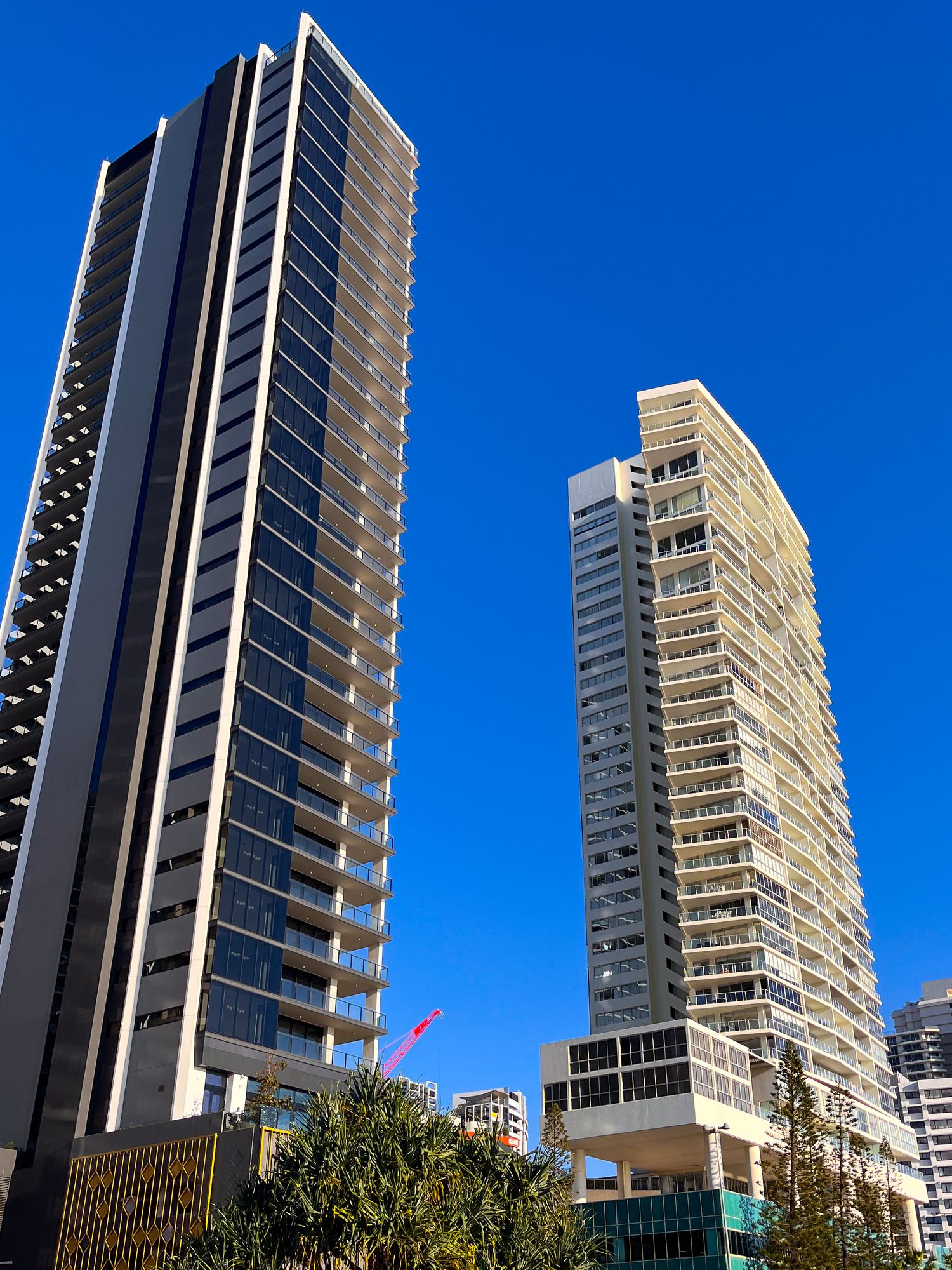 Two modern glass and concrete skyscrapers towering against clear blue sky in city.