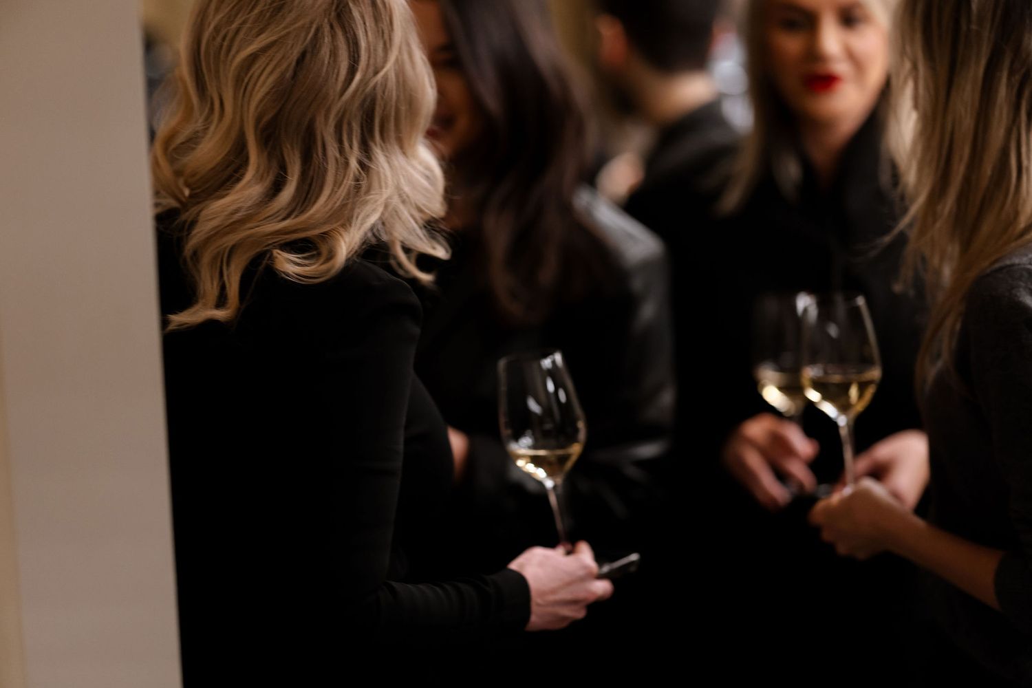Elegant gathering with people holding wine glasses in formal attire.