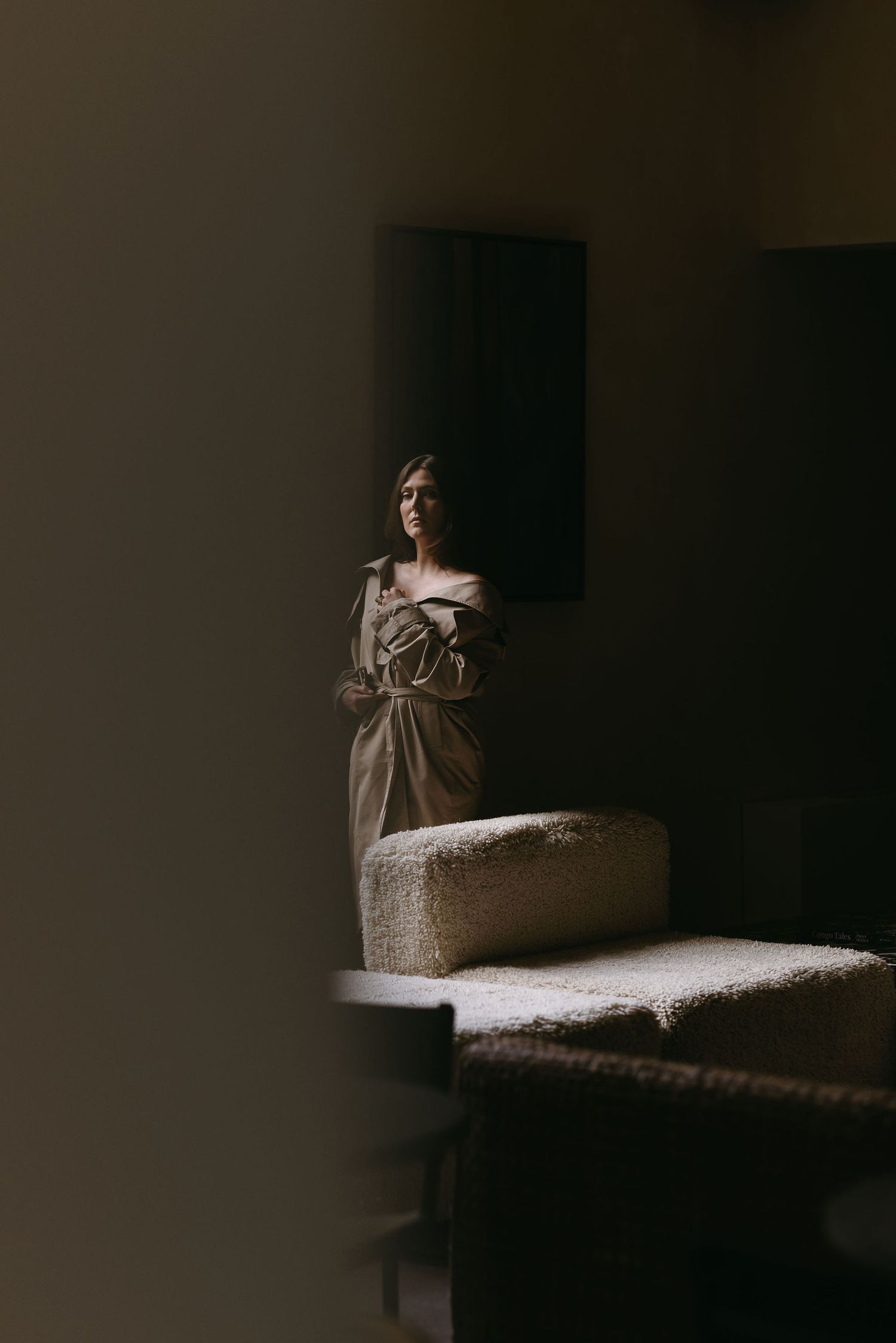 Moody indoor portrait with dramatic lighting and textured furniture in the foreground.
