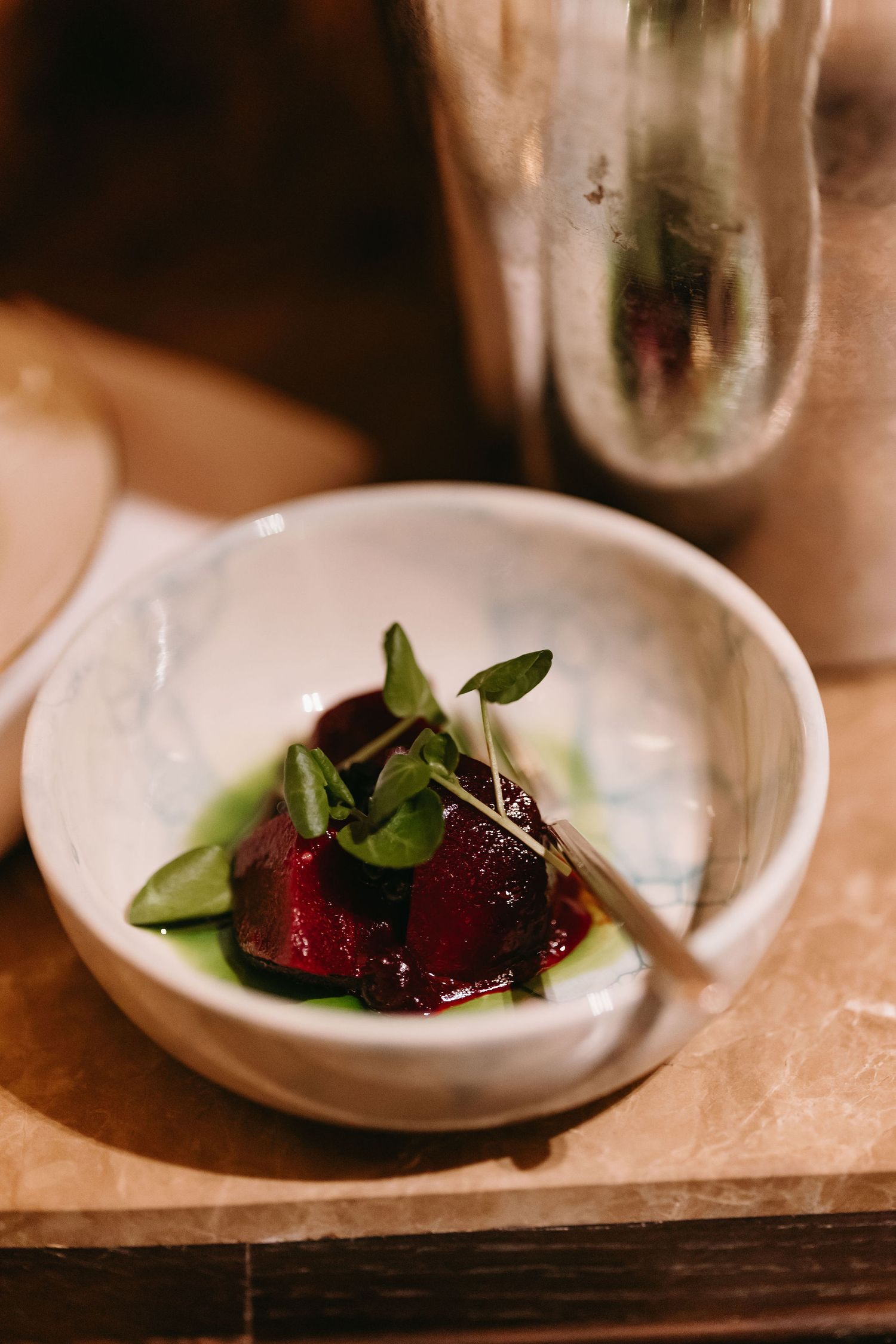 A beautifully plated dish with microgreens and beets in a white bowl.