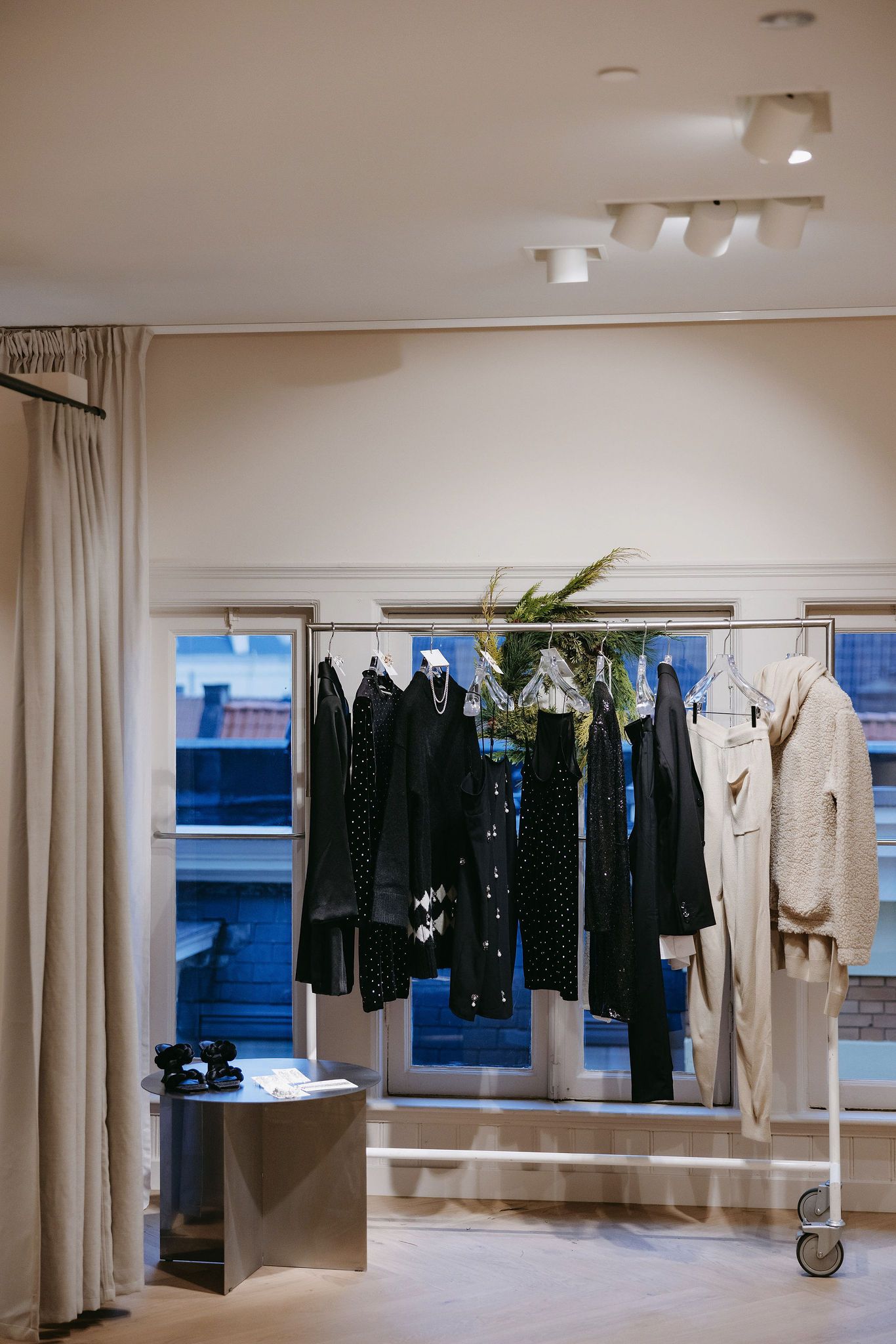 Minimalist clothing display with black and white garments on rack against beige walls.