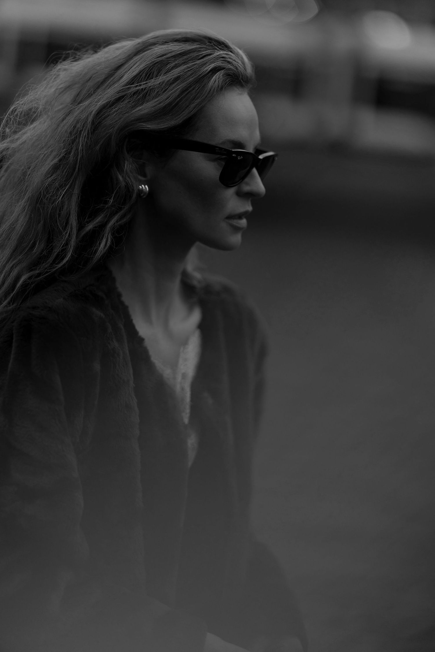 Dramatic black and white profile shot with sunglasses and windswept hair.