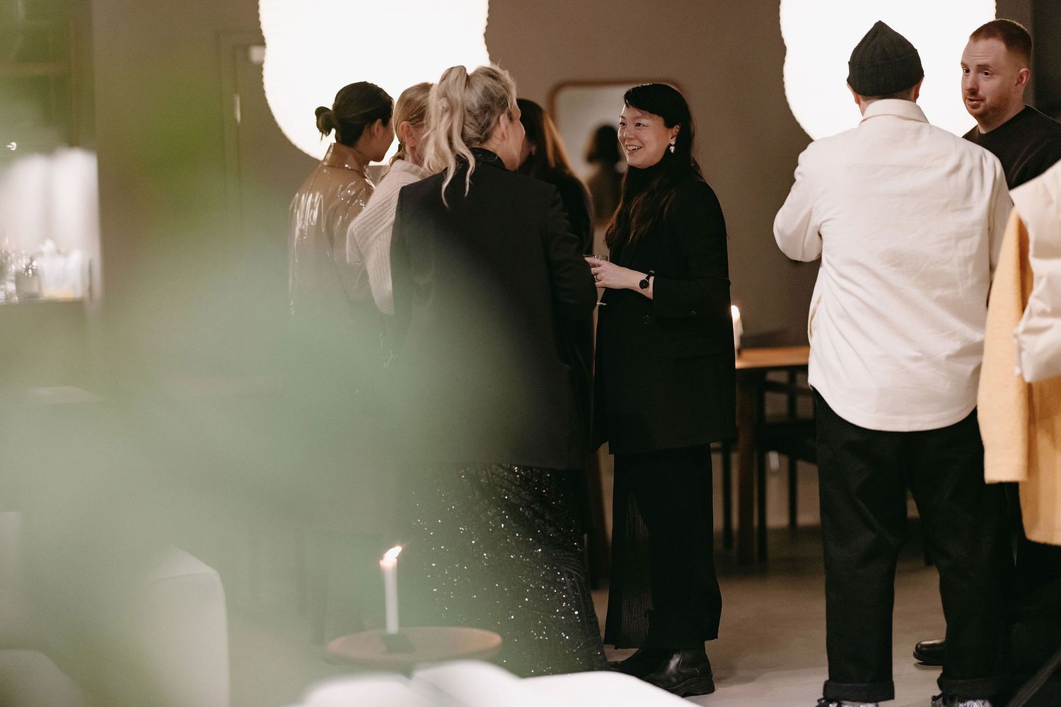 A small group of people in dark clothing having a discussion in a modern indoor setting.