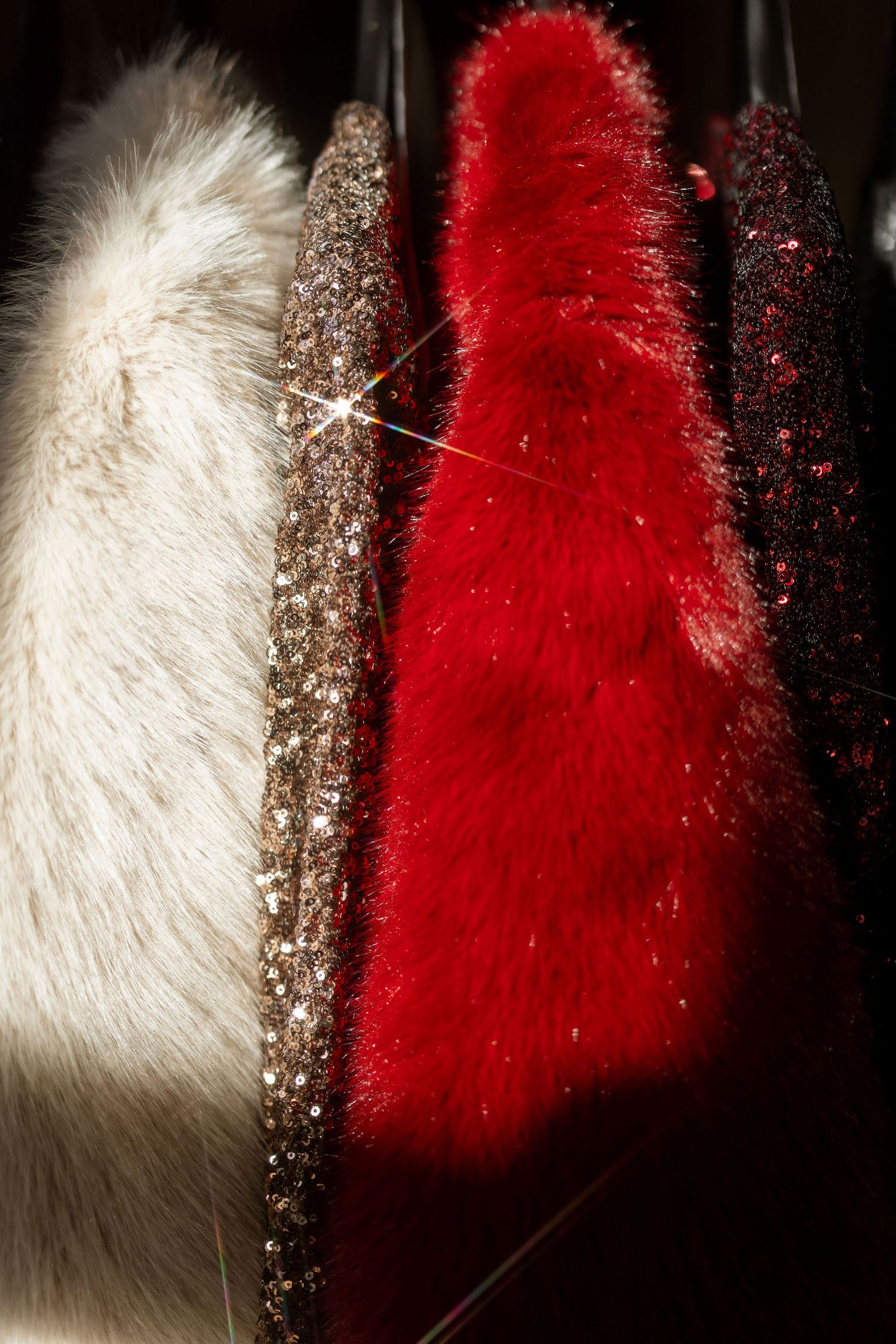 Close-up of luxurious fur garments in white, glittery gold, and bright red colors.