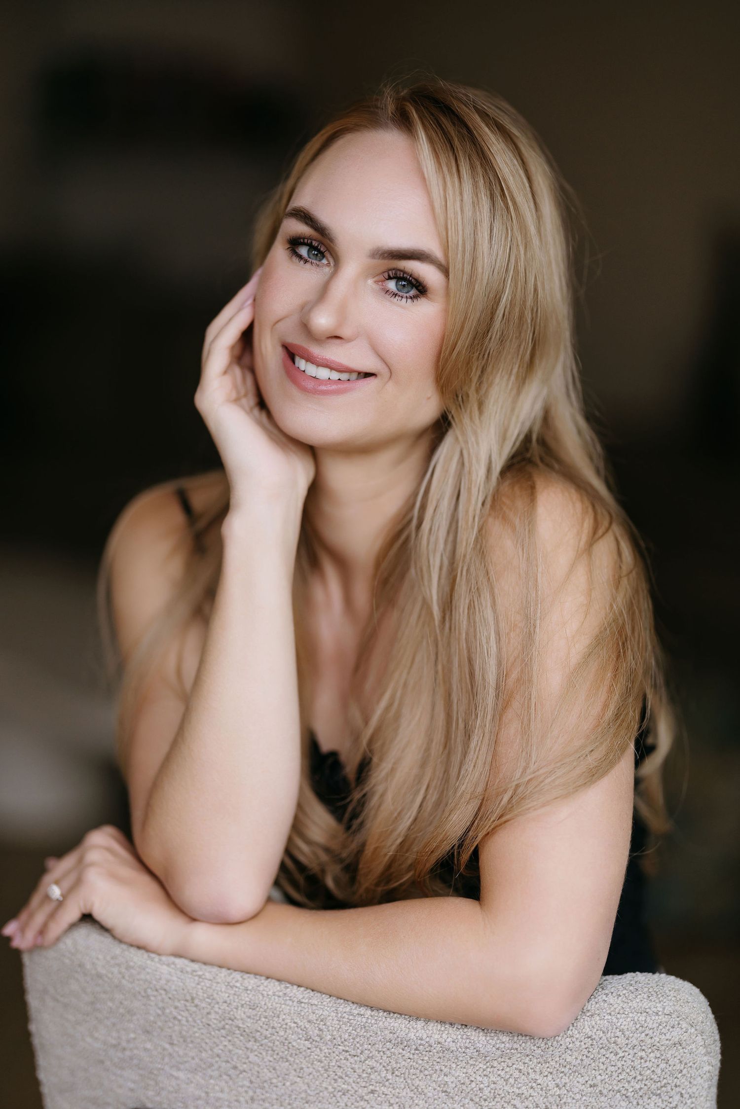 Soft indoor portrait with gentle smile and natural lighting against neutral background.