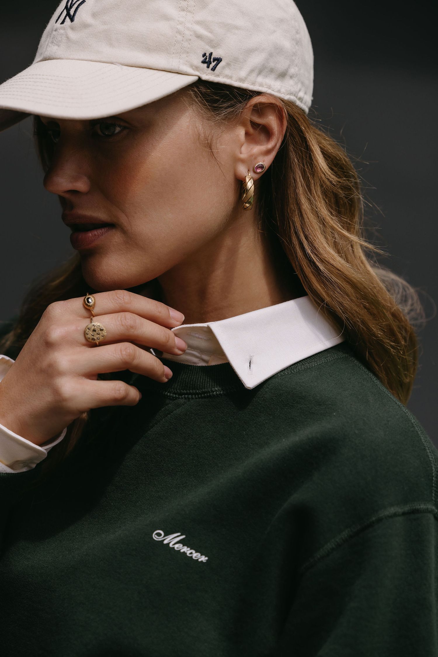 Close-up fashion shot of person wearing NY cap and green sweater with white collar.