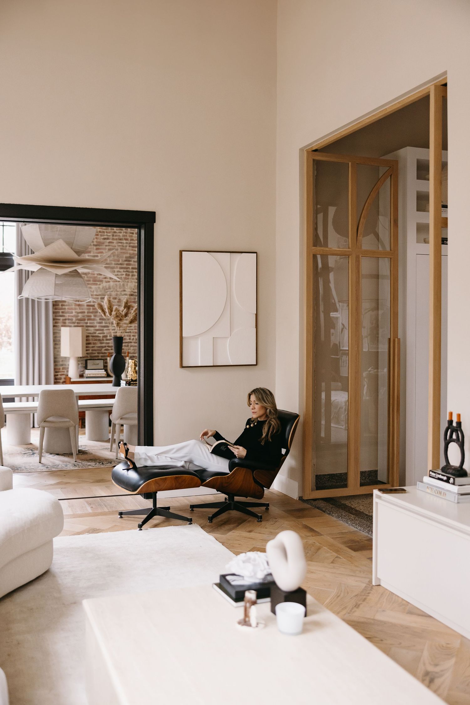 Modern living room interior with person relaxing in lounge chair near abstract wall art.